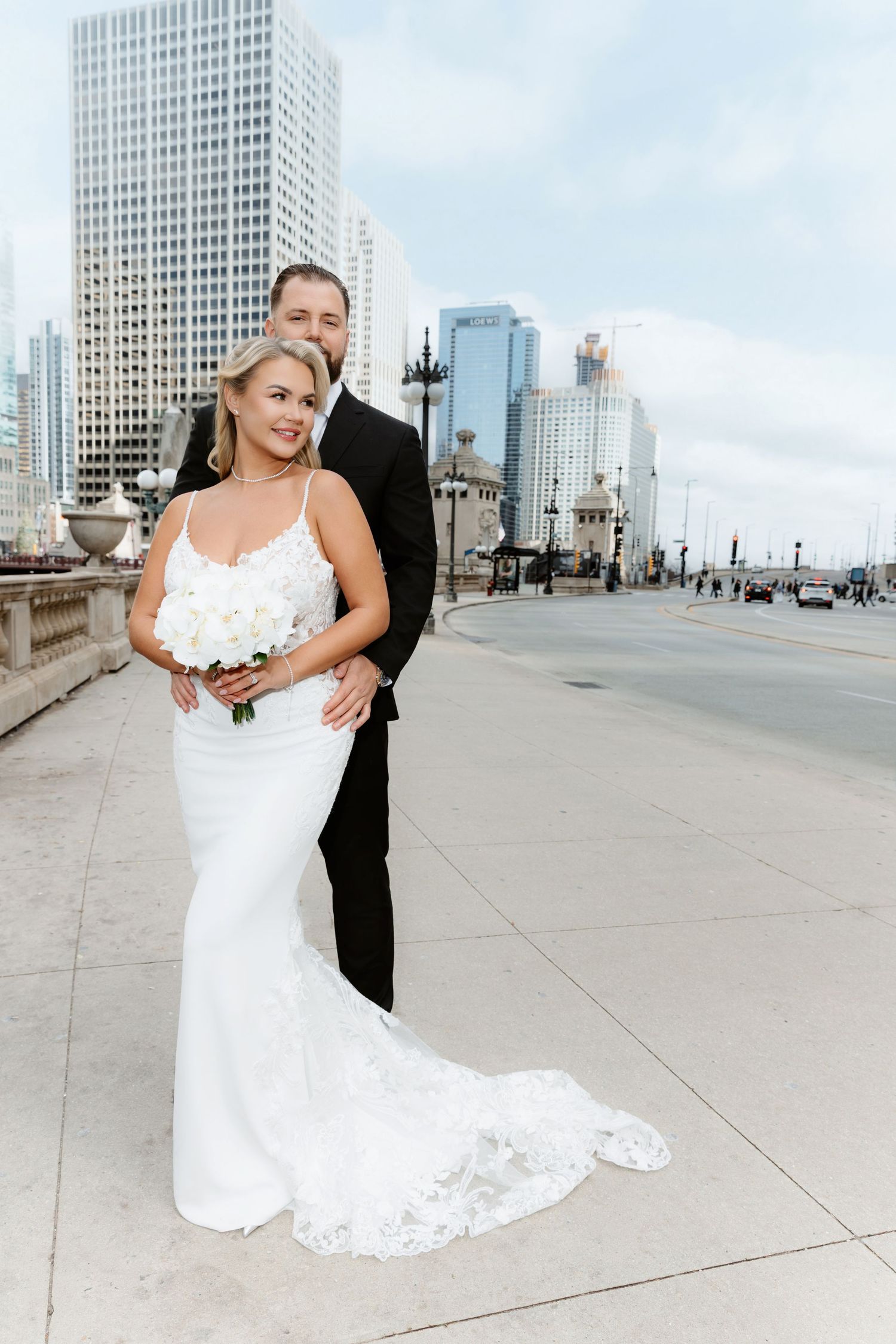 Smiling bride and groom posing together on a Chicago bridge with a stunning city skyline backdrop.