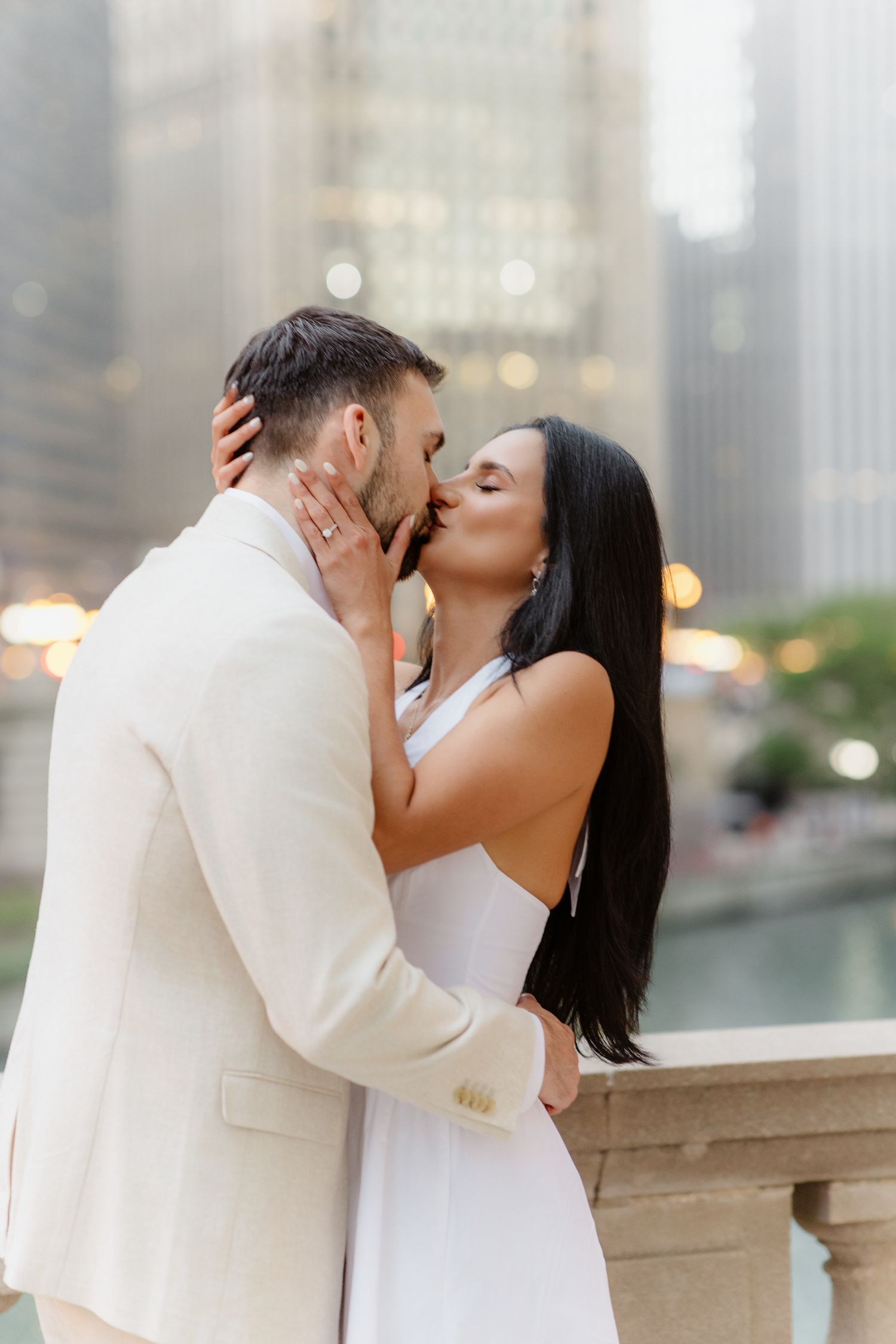 Couple sharing a passionate kiss with Chicago River and city skyline softly blurred in the background.