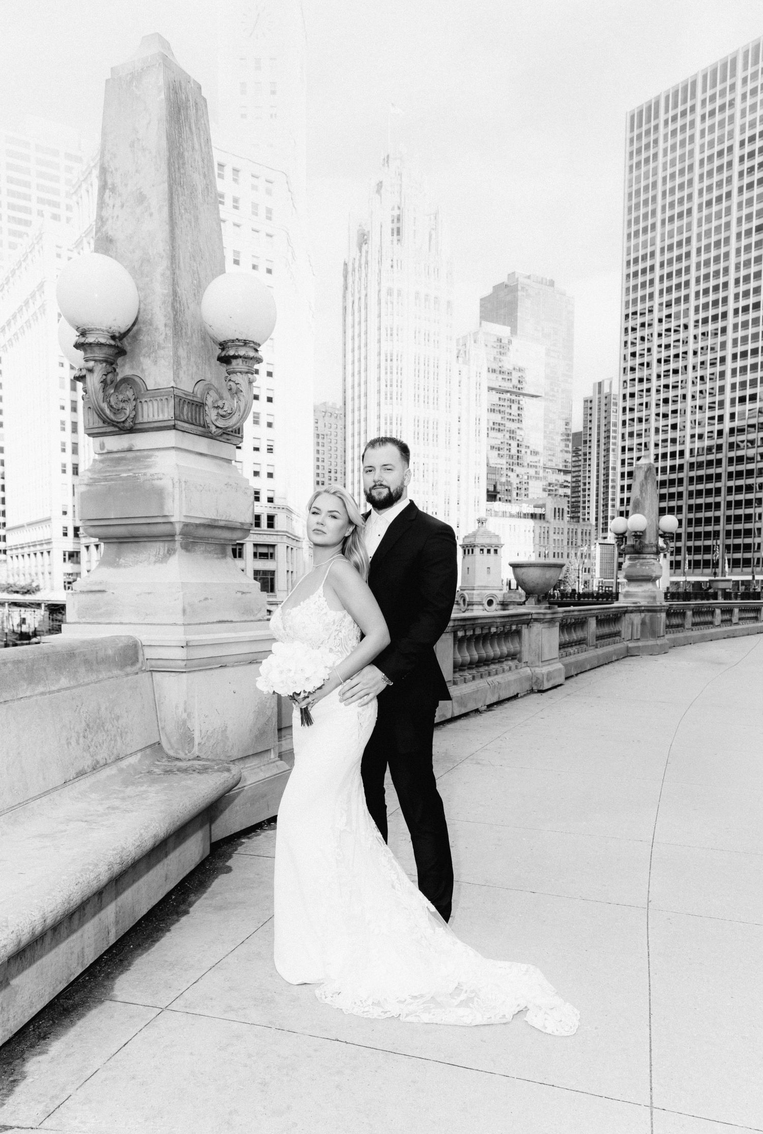 Black and white wedding portrait of couple on Chicago bridge with Wrigley Building backdrop.