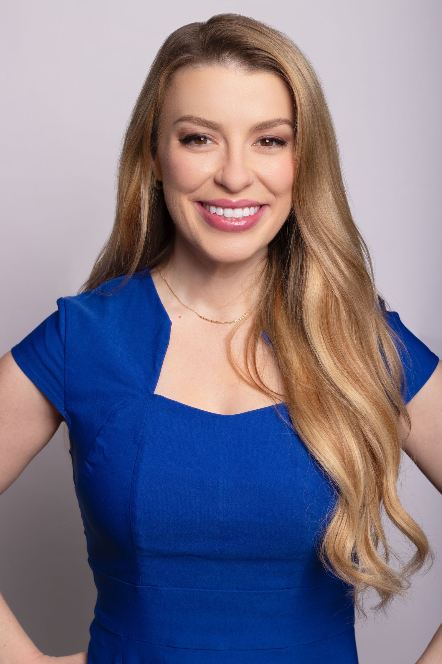 Professional realtor headshot of a blonde woman in a royal blue dress smiling confidently in Charleston, SC.