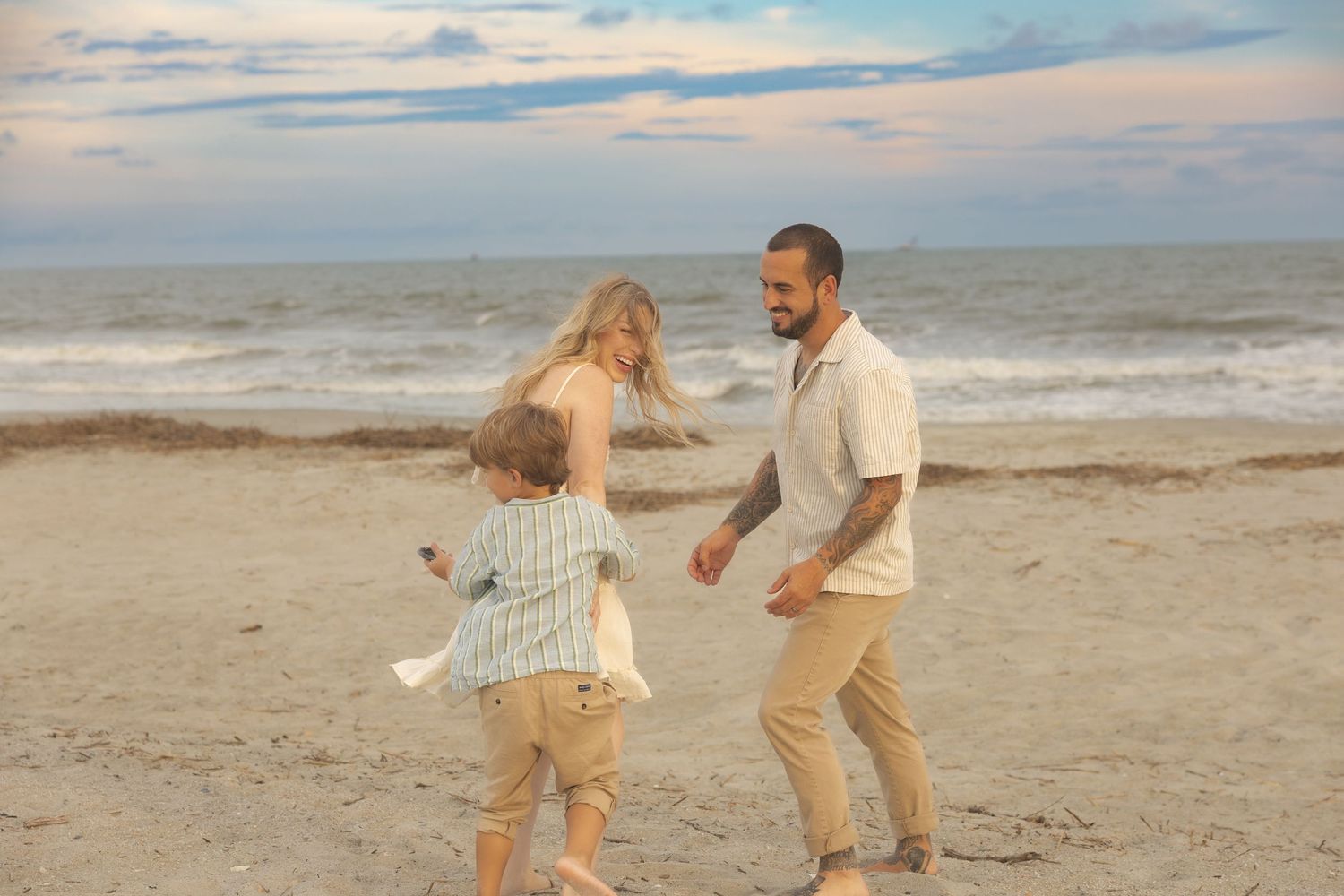 A joyful family plays together on Isle of Palms with ocean waves in the background.