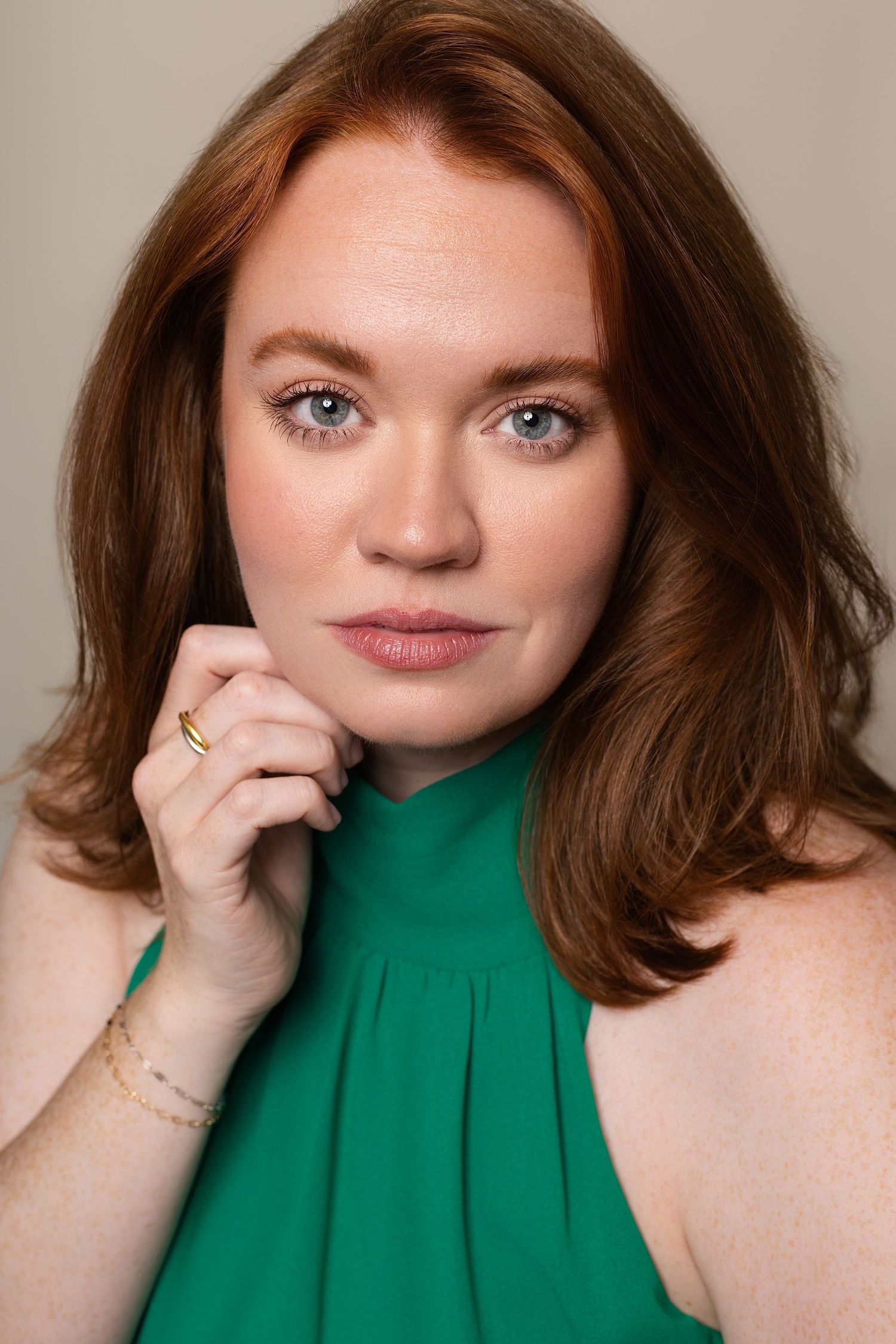 Portrait of a confident redhead woman with blue eyes wearing a green sleeveless top in Charleston.