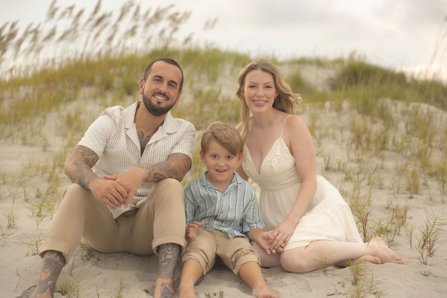 A tattooed father, blonde mother, and young son sit for family portraits on Isle of Palms in South Carolina.