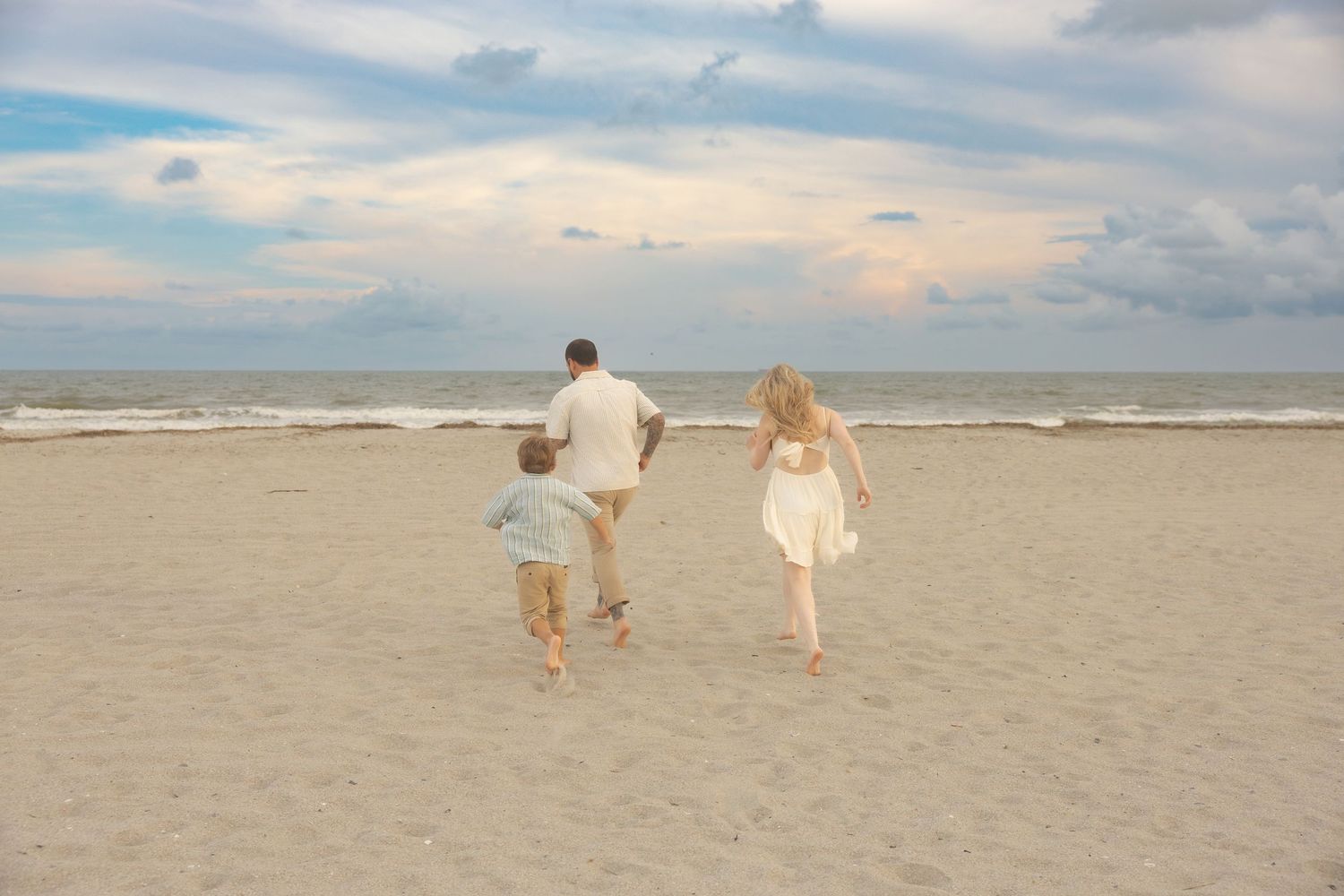 A family of three runs towards the beach at dusk on Isle of Palms.