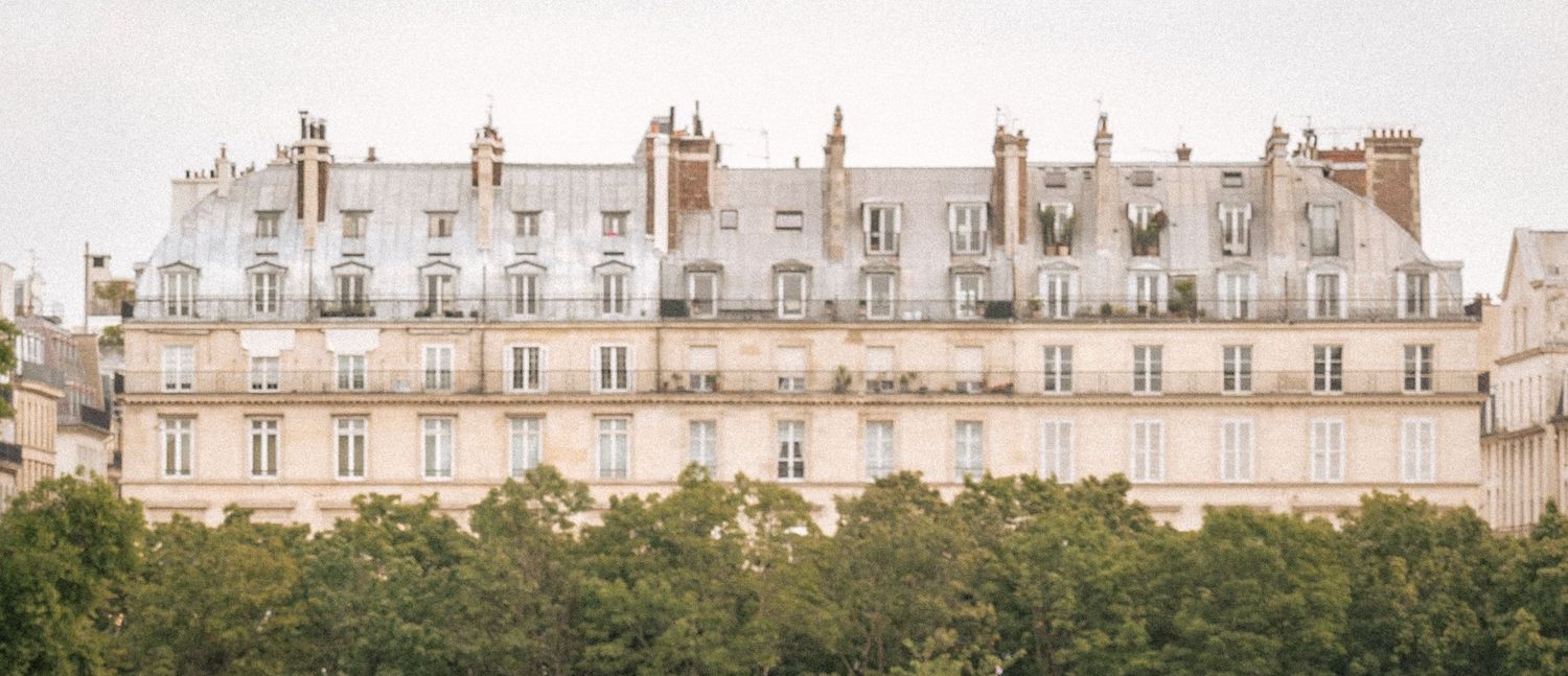 Elegant Haussmann-style Parisian apartment building facade with white stone architecture and classic French windows.