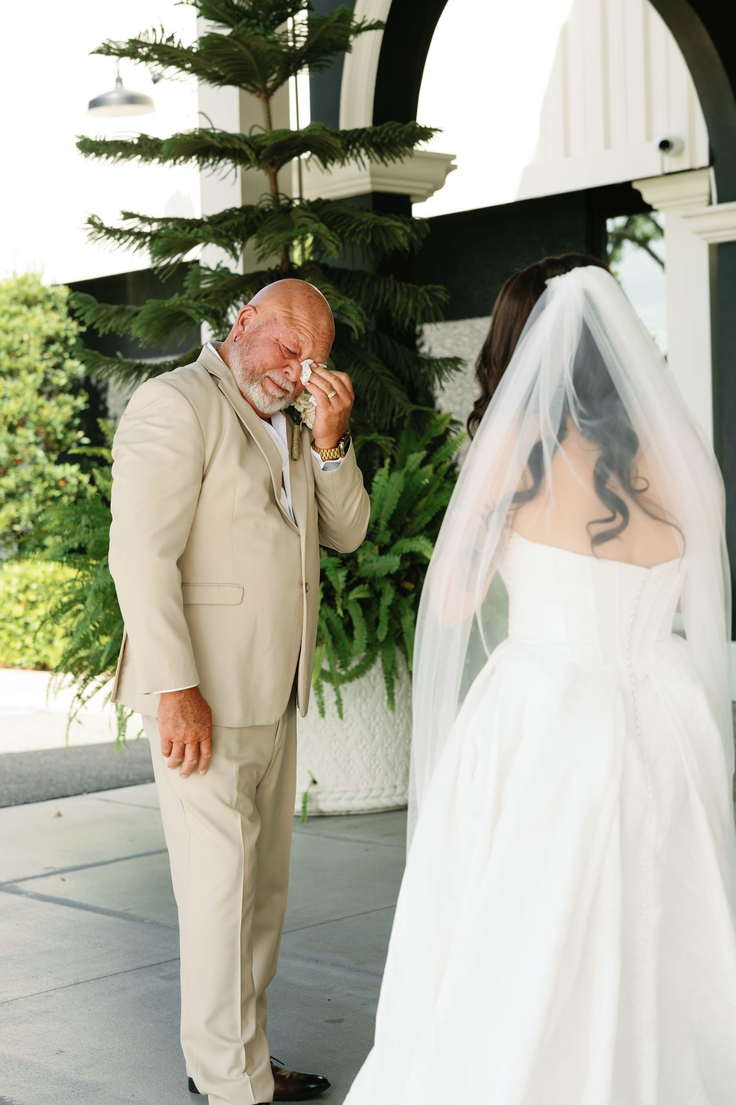 Emotional father wipes tears seeing his daughter in her wedding dress during a heartfelt first look moment.