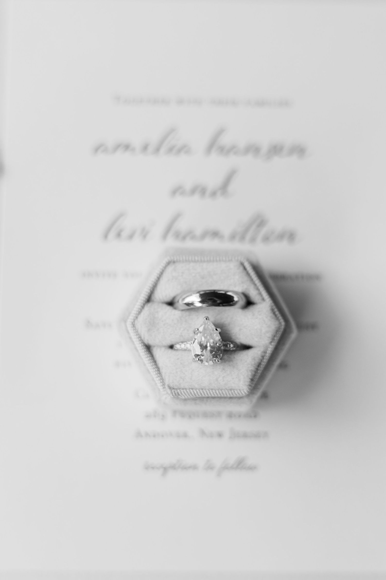 Diamond engagement ring and wedding band in velvet box on wedding invitation.