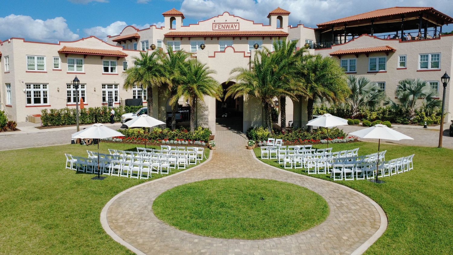 Aerial view of elegant outdoor wedding ceremony setup with white chairs at historic Florida venue.