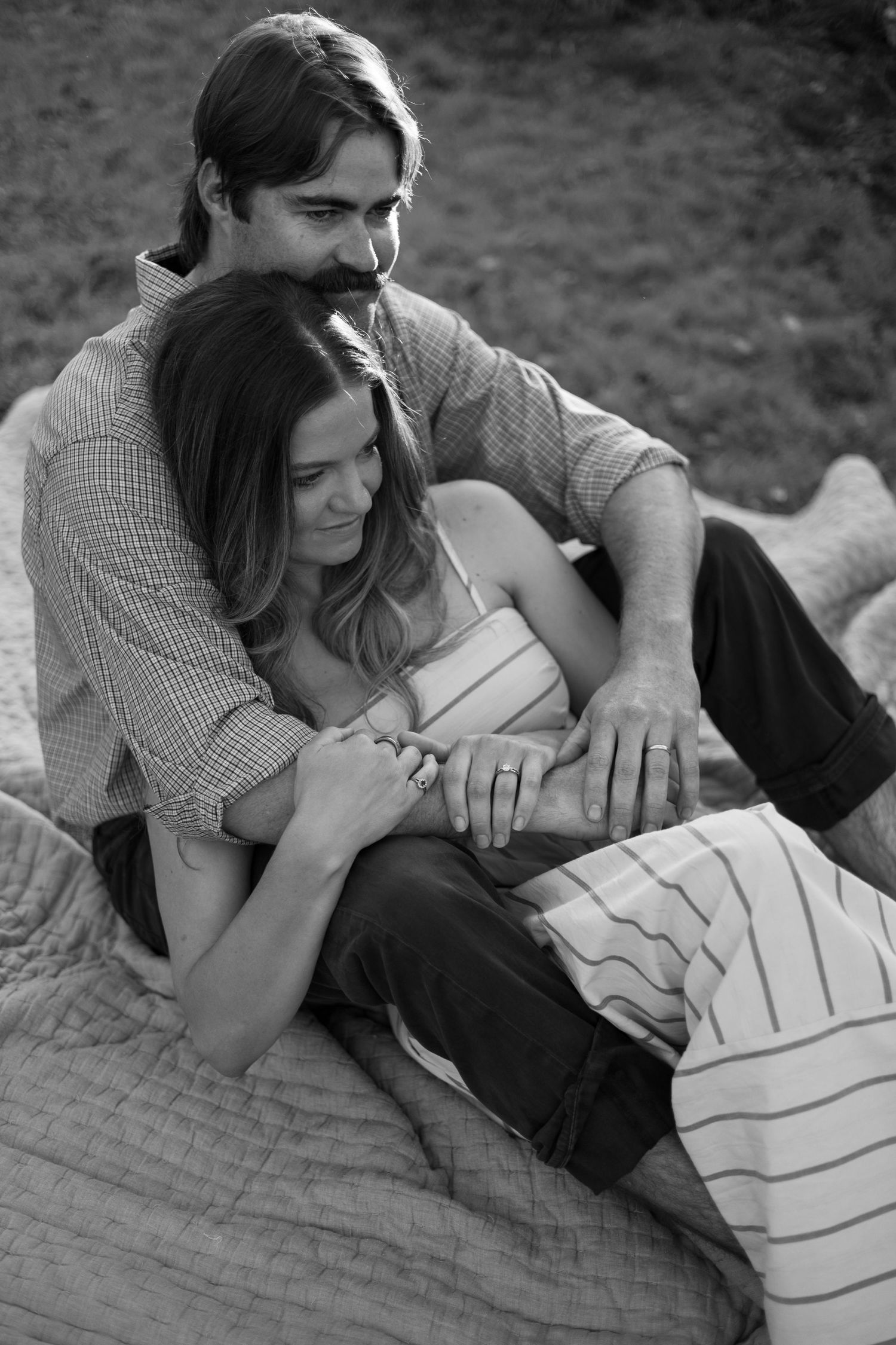 Black and white photo of couple relaxing together on a blanket outdoors.