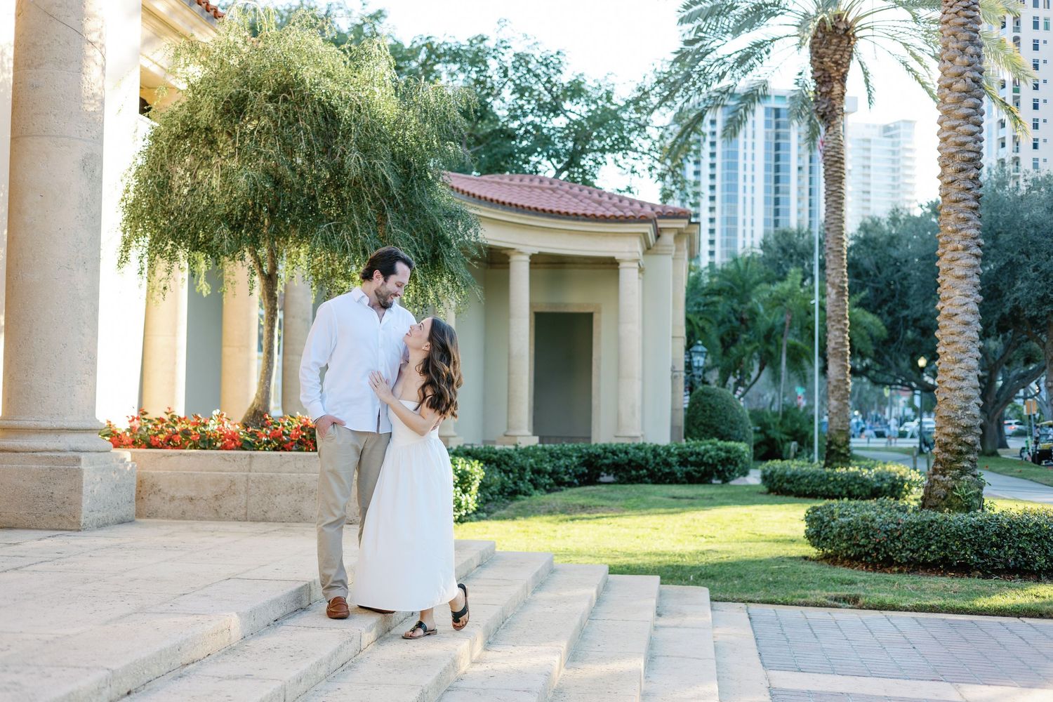 Happy couple walking down outdoor steps in lush garden with palm trees.