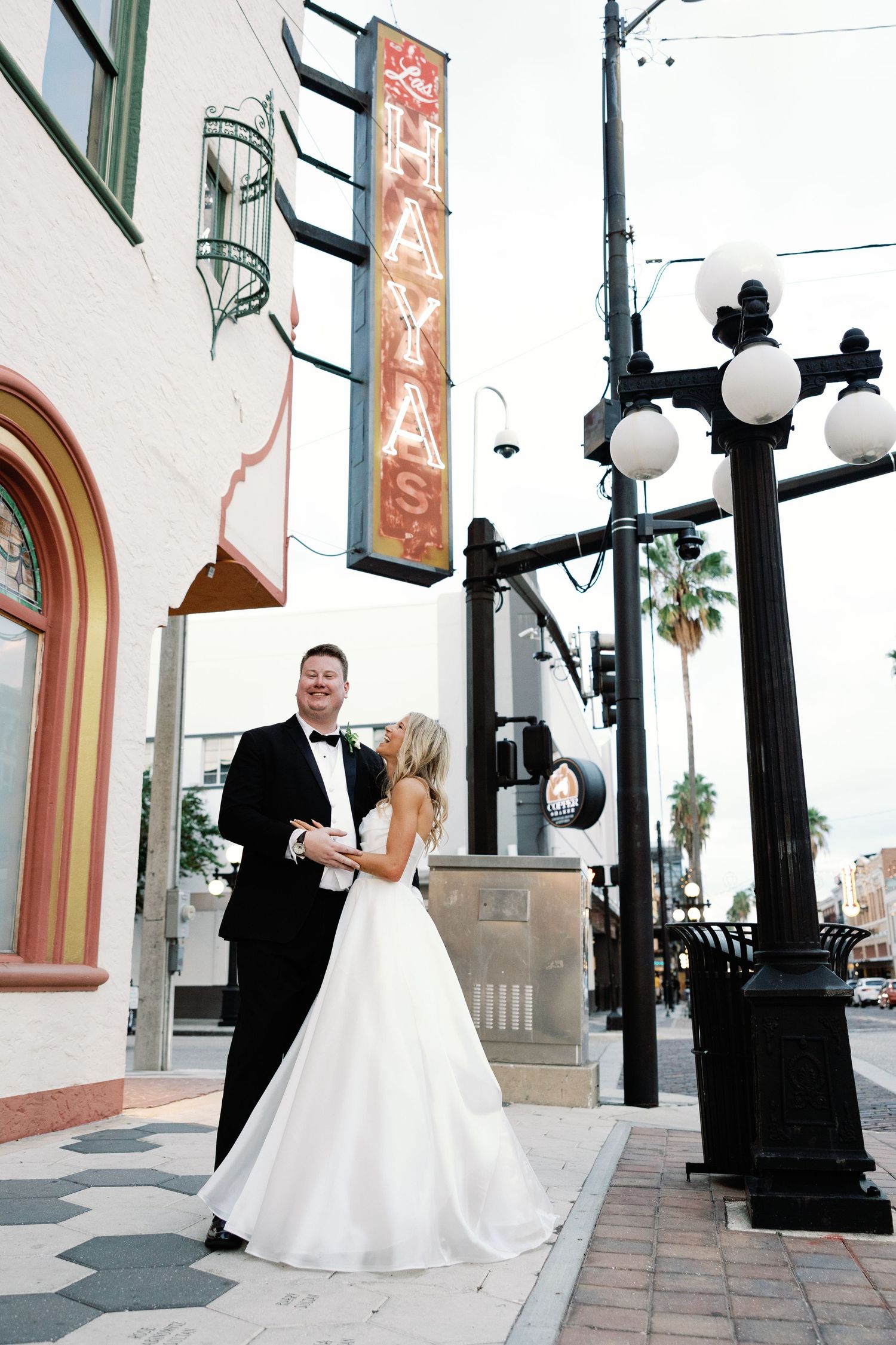 Bride and groom dancing outside iconic Haya's restaurant sign in Ybor City Tampa at dusk.