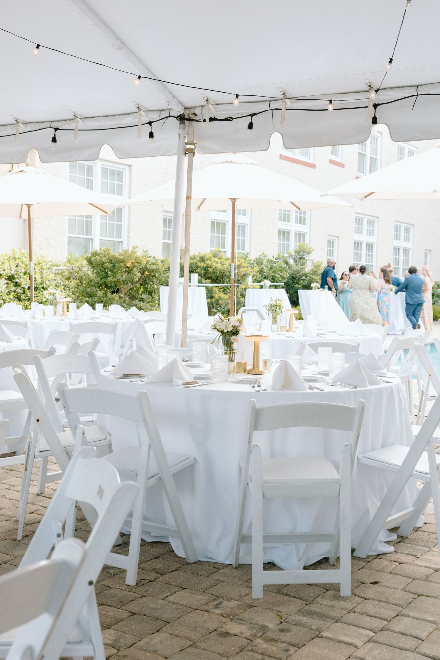 Elegant outdoor wedding reception under white tent with round tables and string lights at Florida venue.