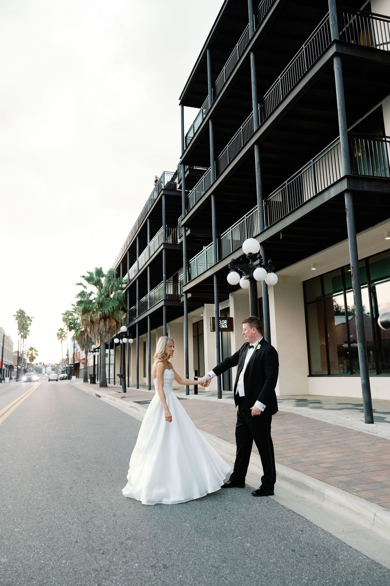 Elegant bride and groom holding hands in street outside historic building in Ybor City Tampa.
