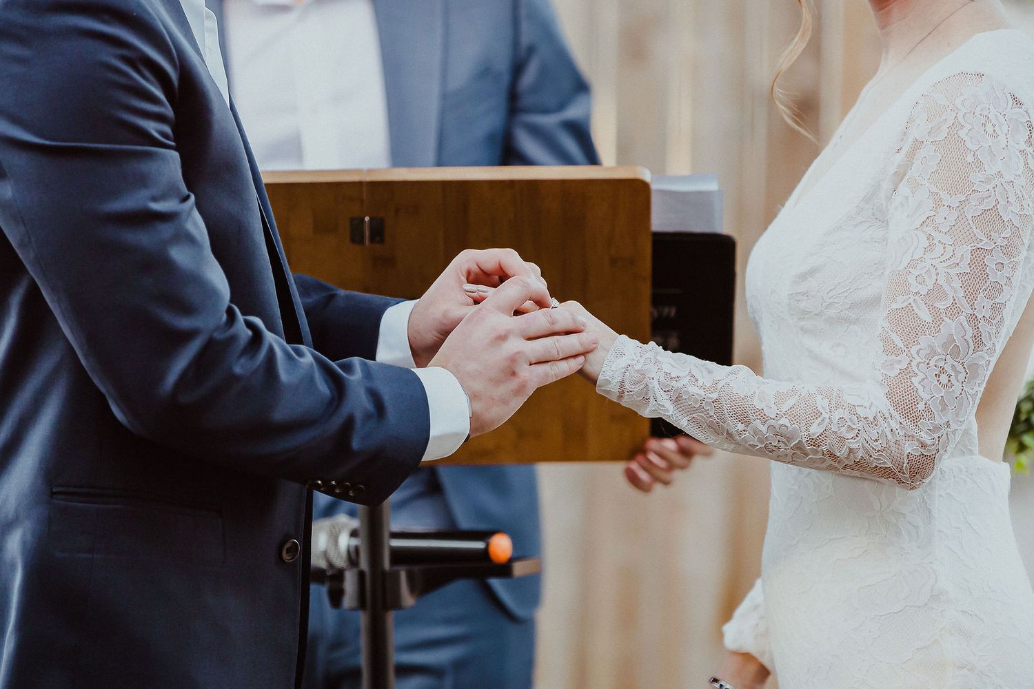Groom places wedding ring on brides finger during intimate ceremony exchange of vows.