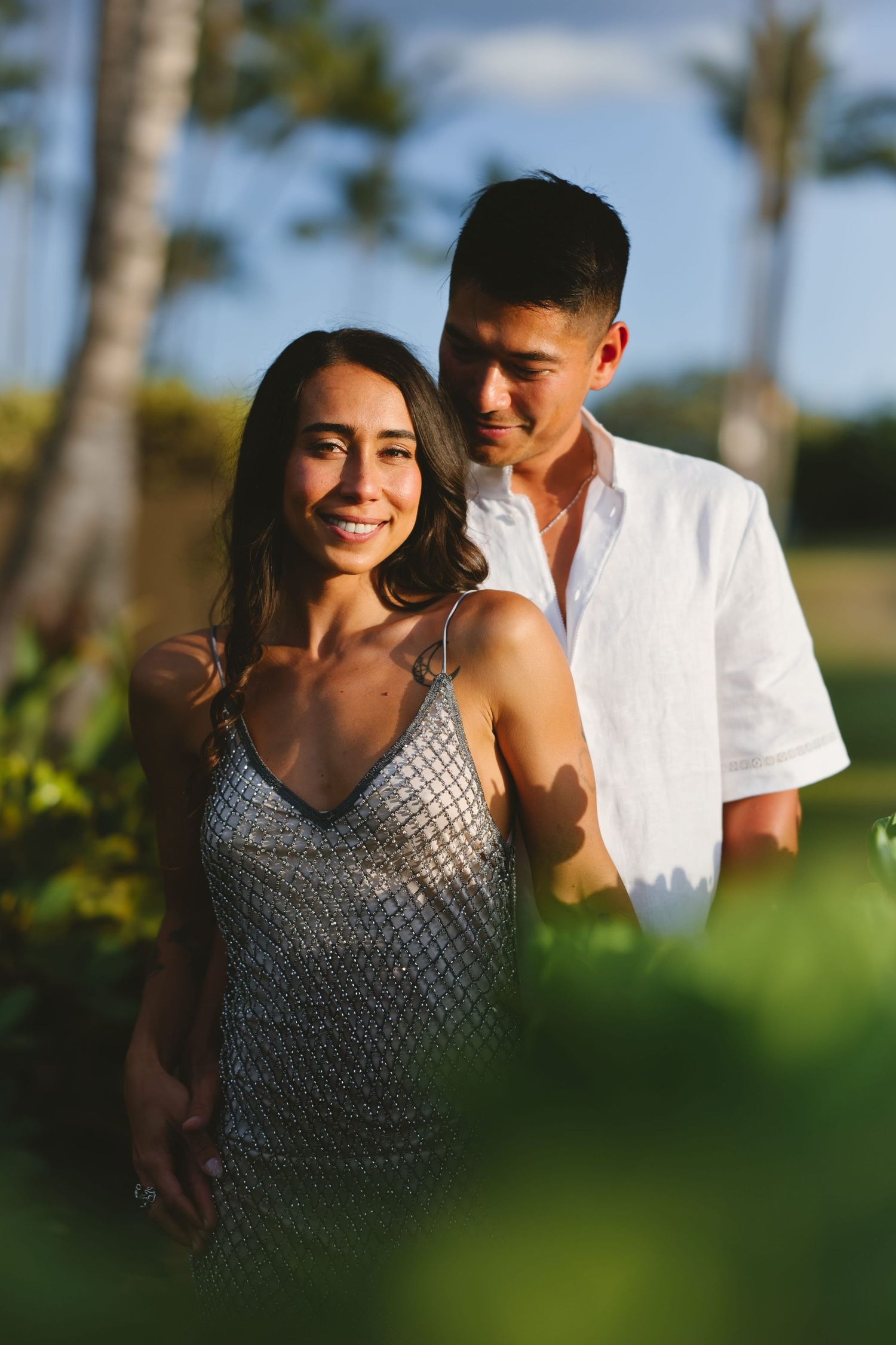 Smiling couple in tropical garden with palm trees at golden hour in Hawaii.
