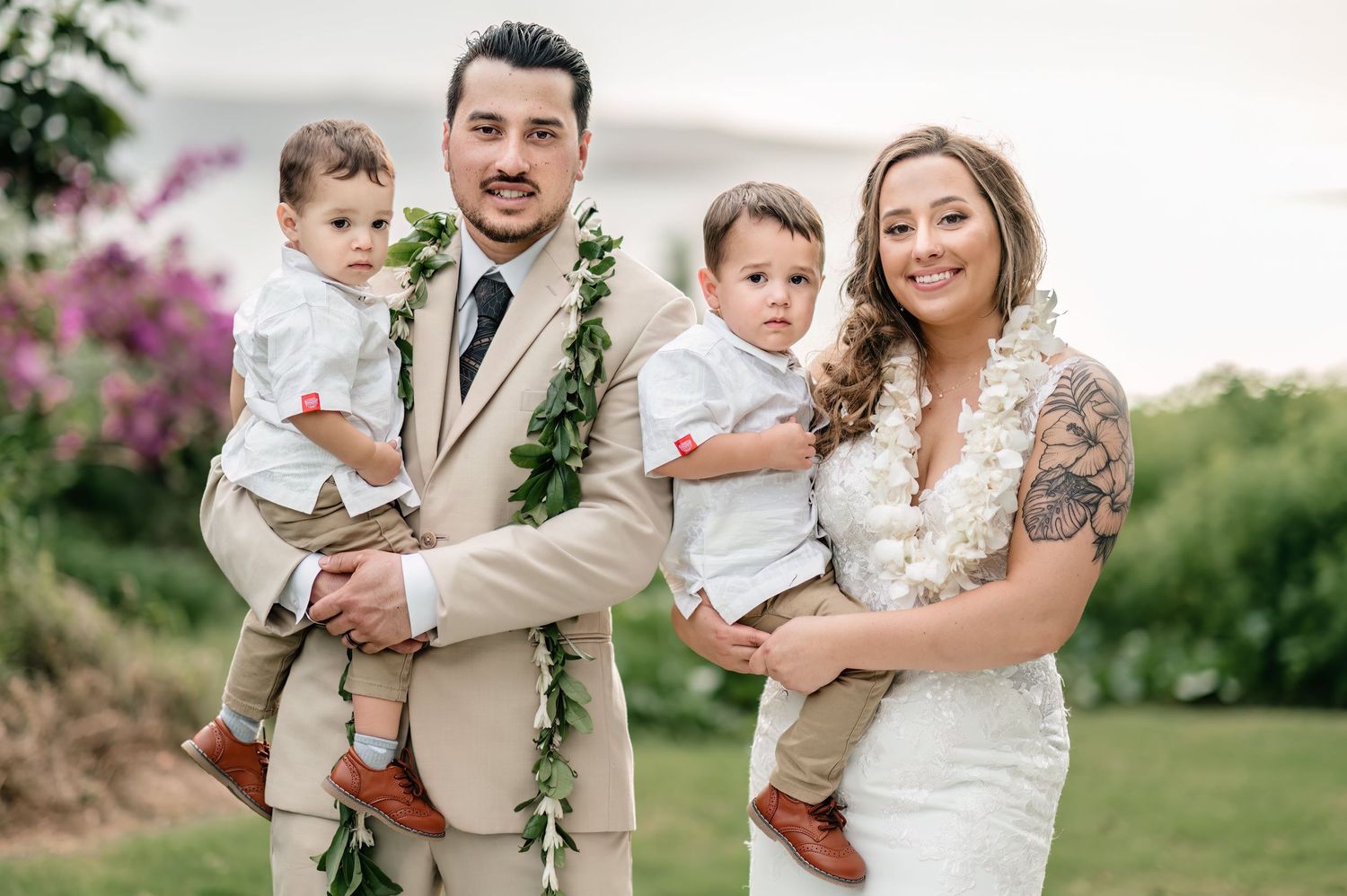 Wedding couple and child share tender moments in a lush garden setting with tropical flowers.