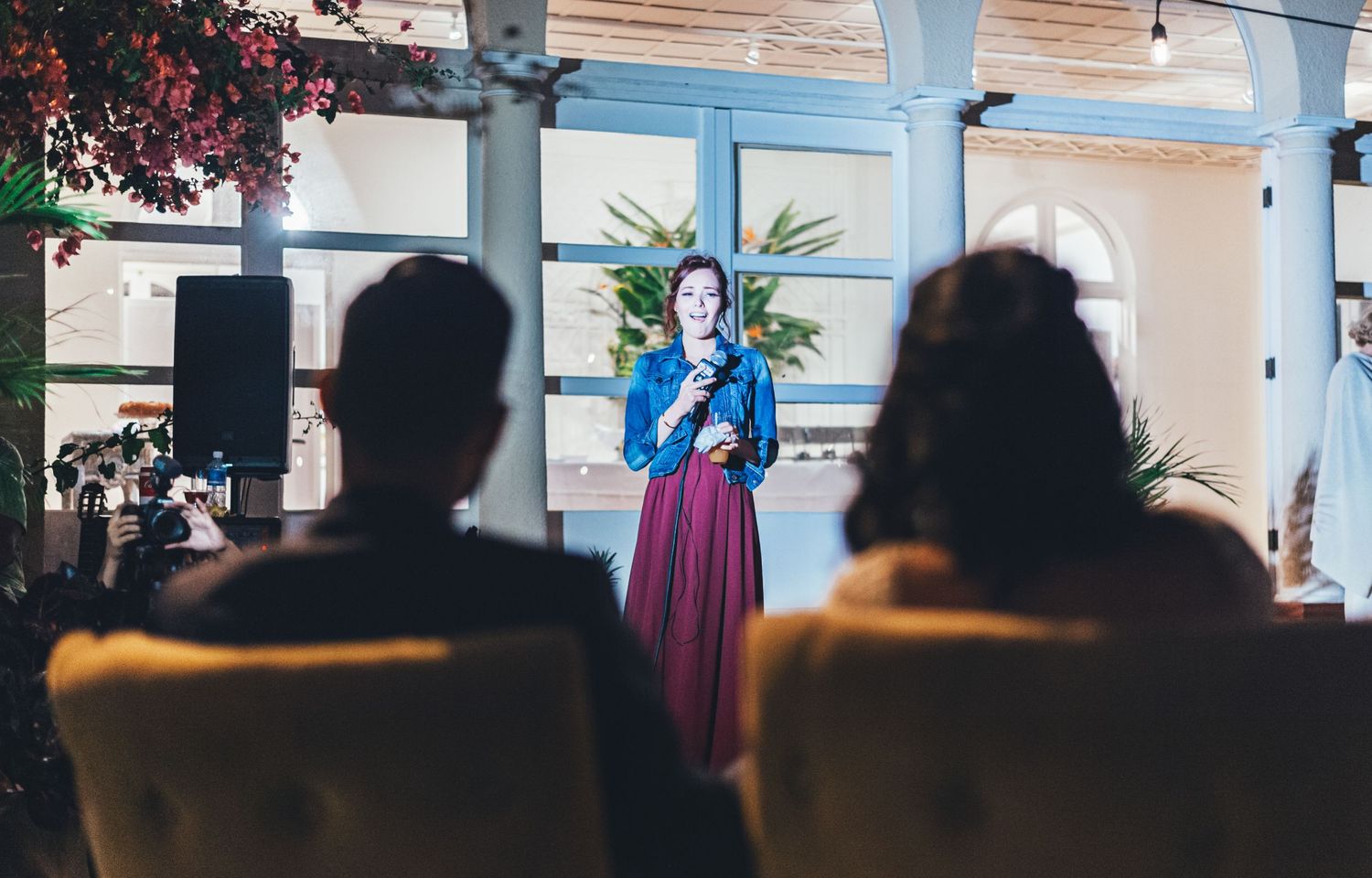 Indoor wedding venue with white columns and audience seated in rows.