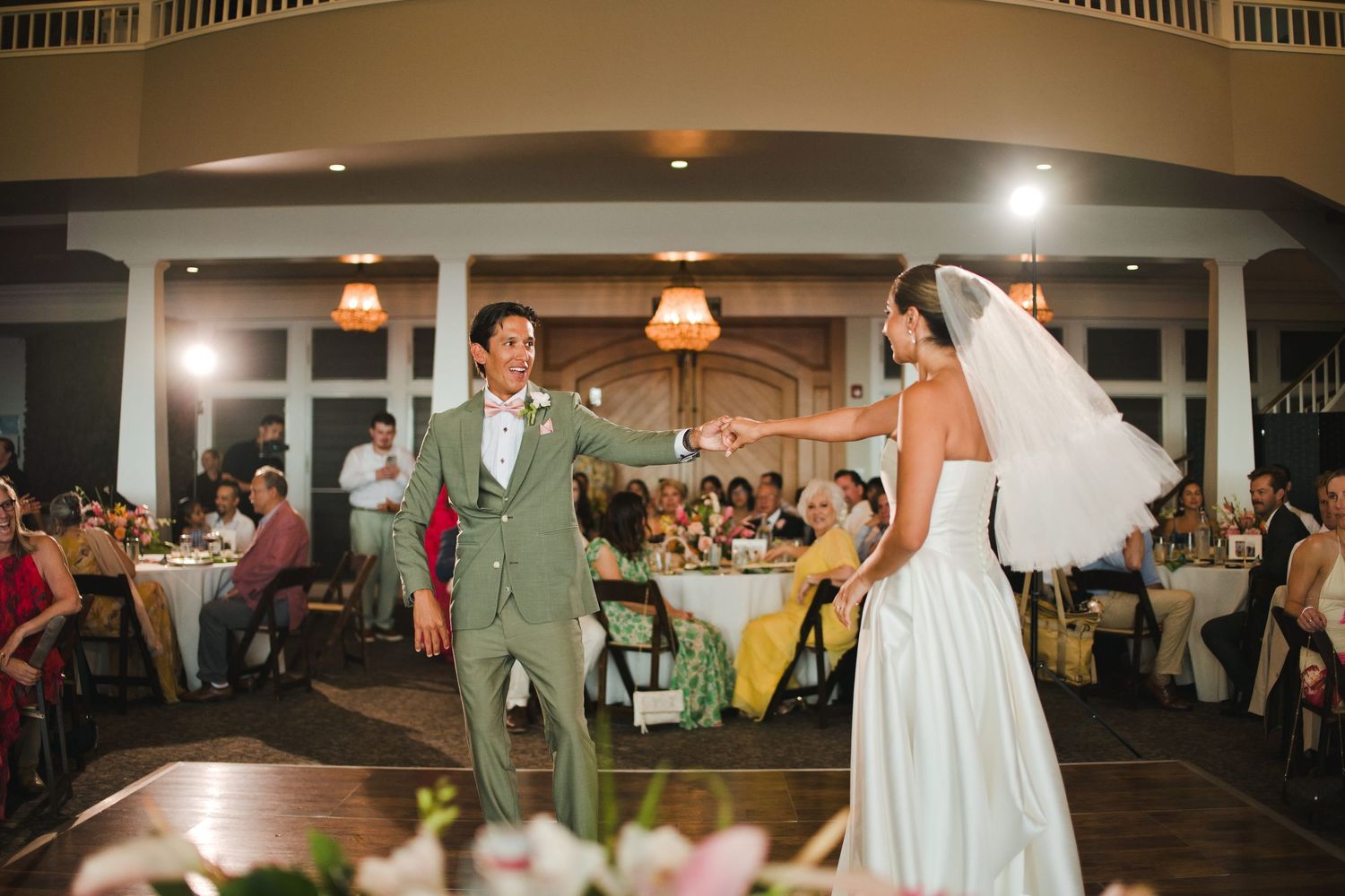 Bride and groom sharing their first dance at a wedding reception in a beautifully lit ballroom.