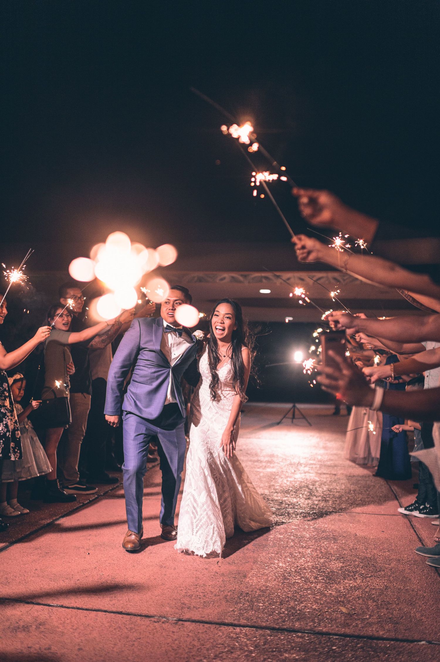 Couple walks through a sparkler send-off line during their wedding exit celebration.