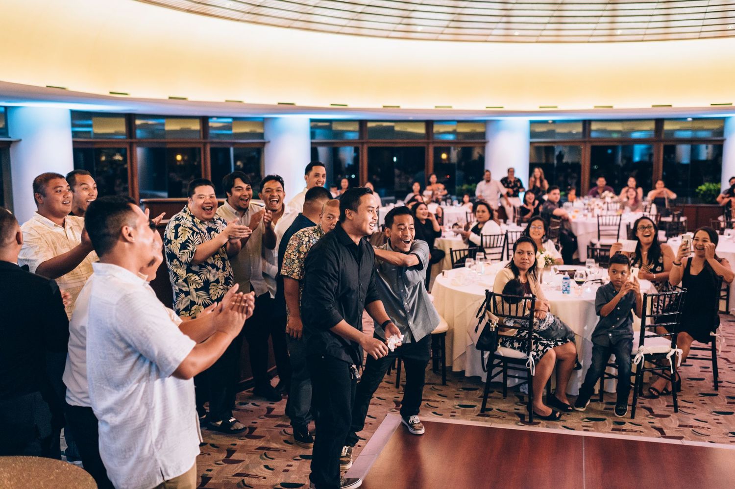 Large banquet hall with curved ceiling details and guests seated at round tables.