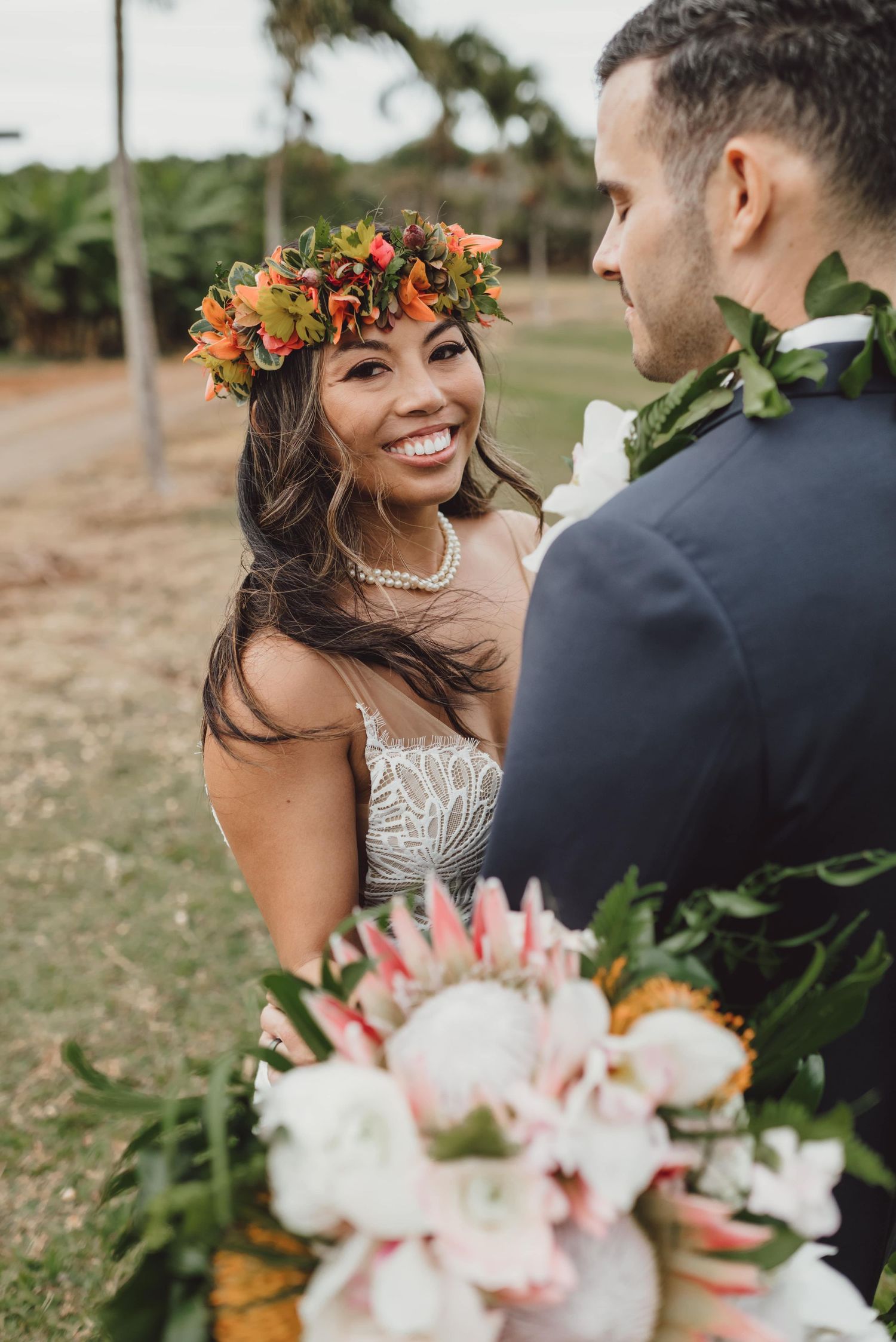 Romantic wedding moments with tropical flower crown and bouquet in outdoor setting.