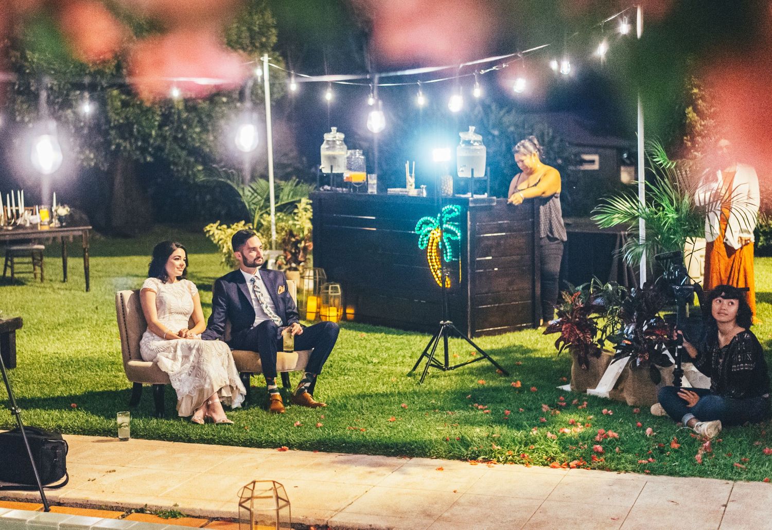 Outdoor nighttime wedding reception with string lights illuminating the garden space.
