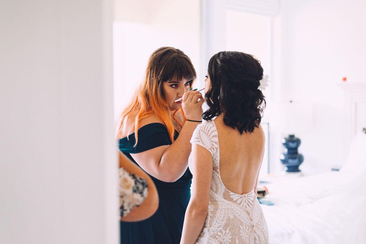 Final wedding dress adjustments being made in a bright white room.
