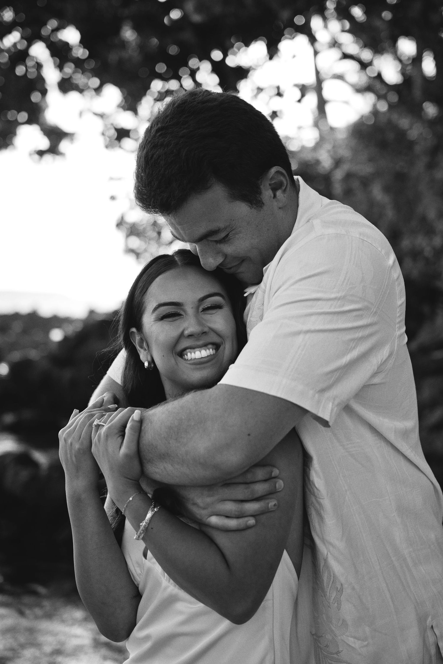 Couple embracing and laughing together in black and white outdoor engagement photo.