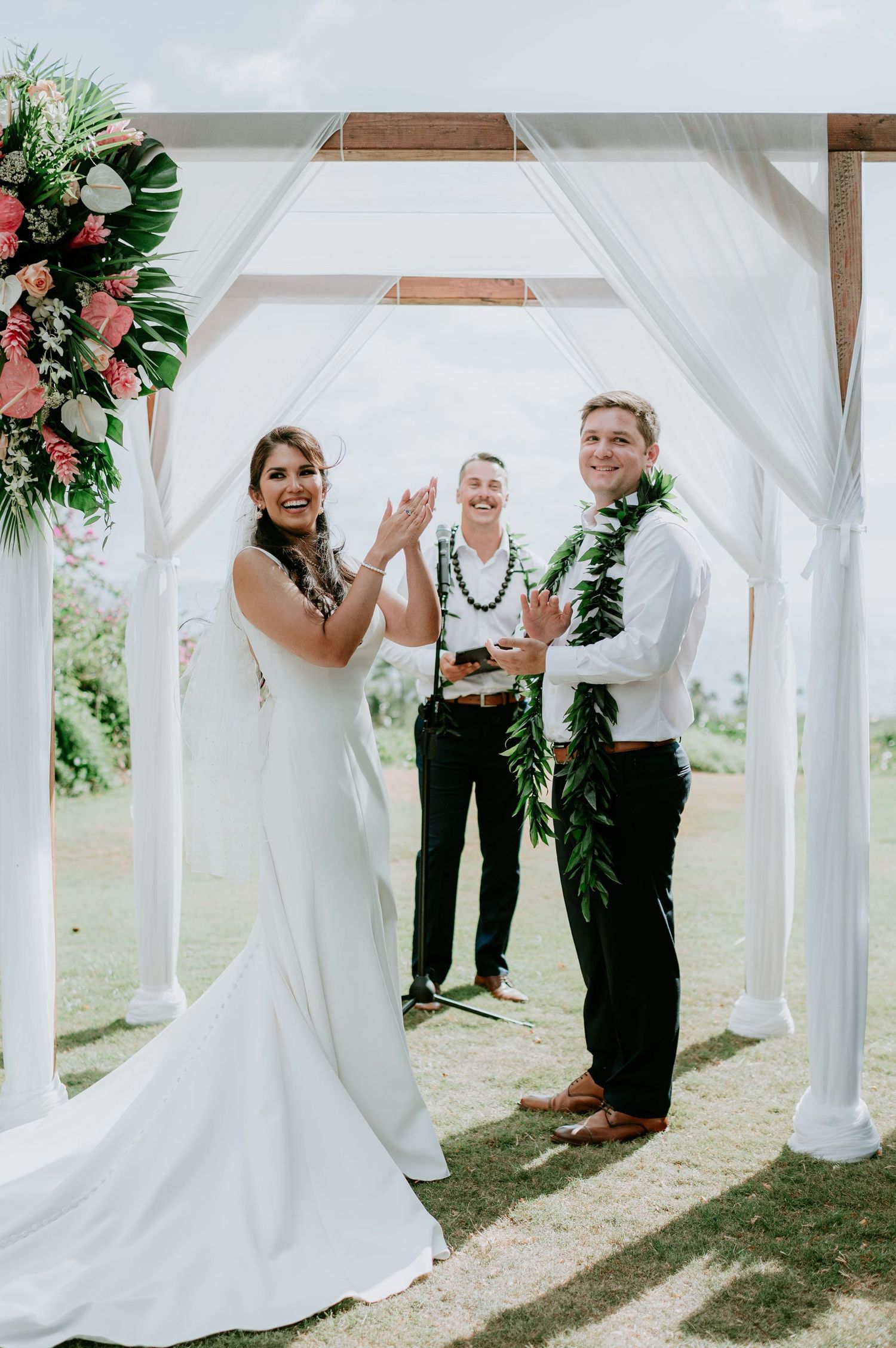 White wedding arbor decorated with pink flowers frames outdoor ceremony moments.