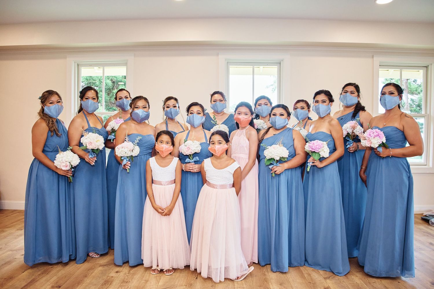 Wedding party poses in coordinating blue and pink dresses during outdoor celebration.