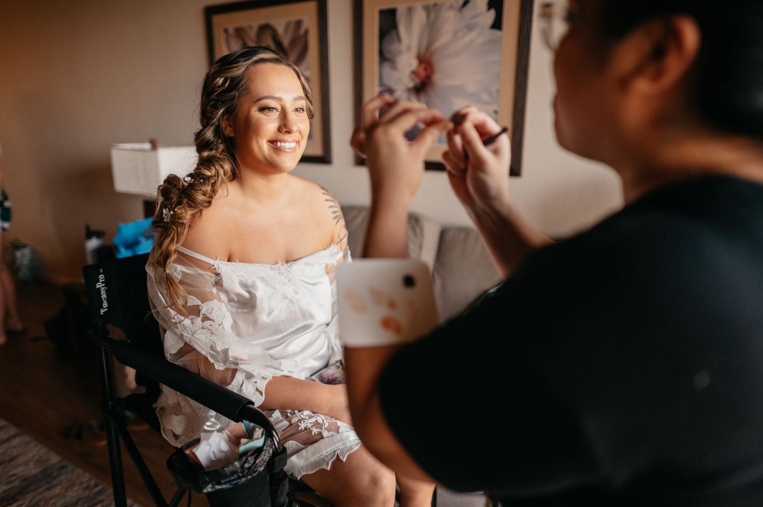 A candid moment of bridal makeup preparation in a warmly lit room.