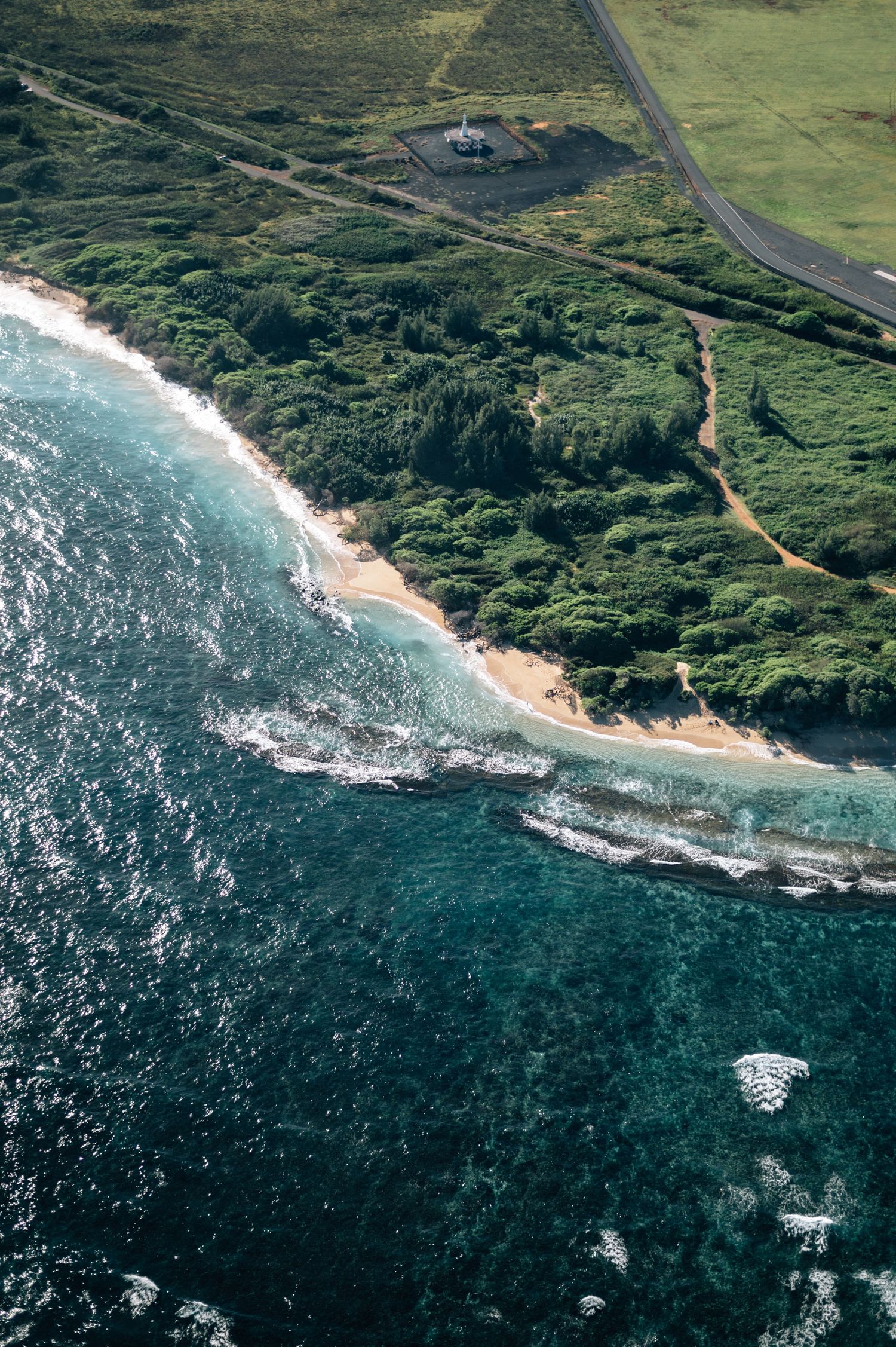 Aerial view of a coastal road alongside turquoise waters and rocky cliffs.
