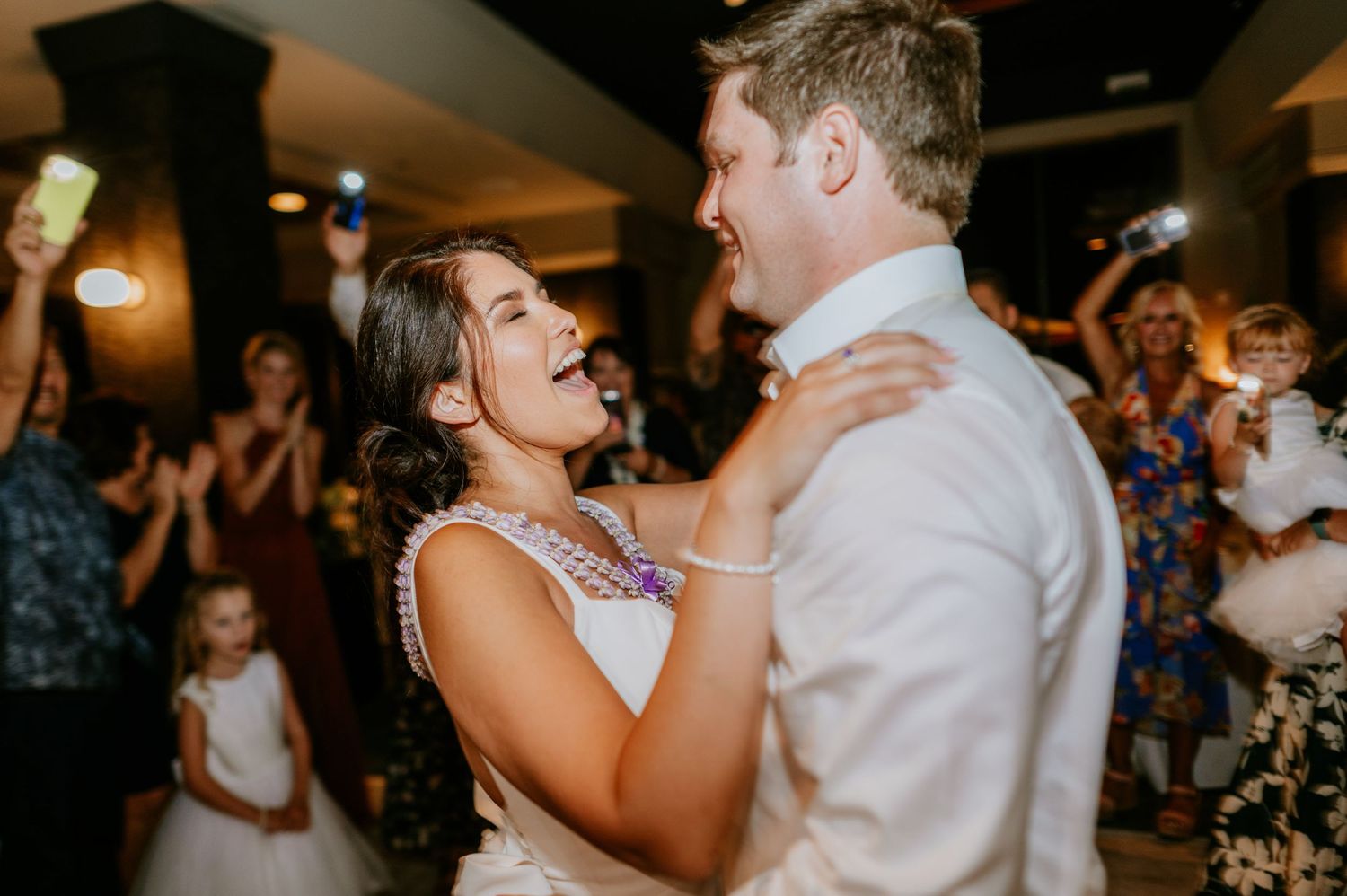 Wedding couple and guests dancing joyfully at an indoor reception celebration.
