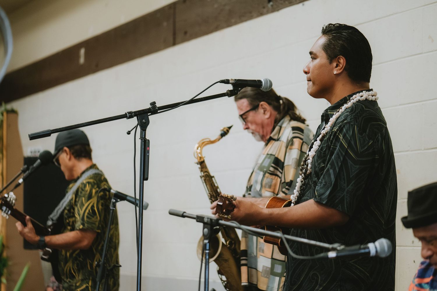 Musicians performing with instruments and microphones at an indoor event.