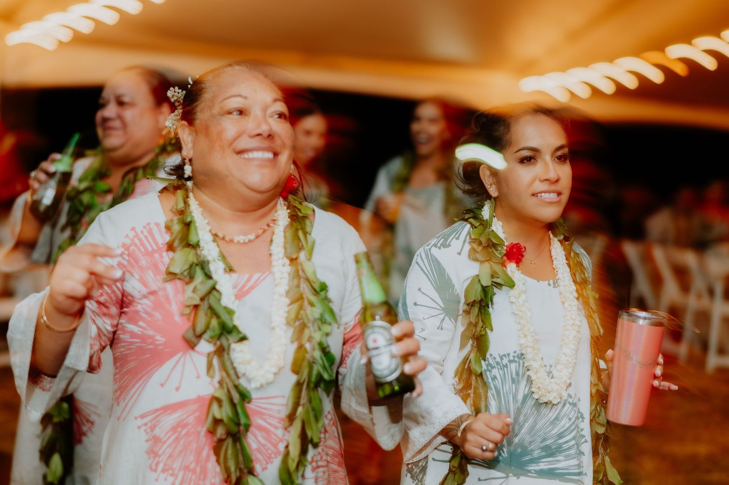 Wedding guests enjoying festivities wearing traditional Hawaiian leis and tropical attire.