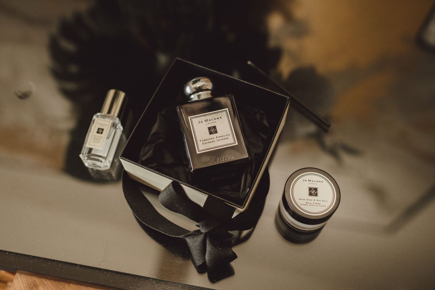 Collection of perfume bottles and wedding accessories arranged on a dark surface.