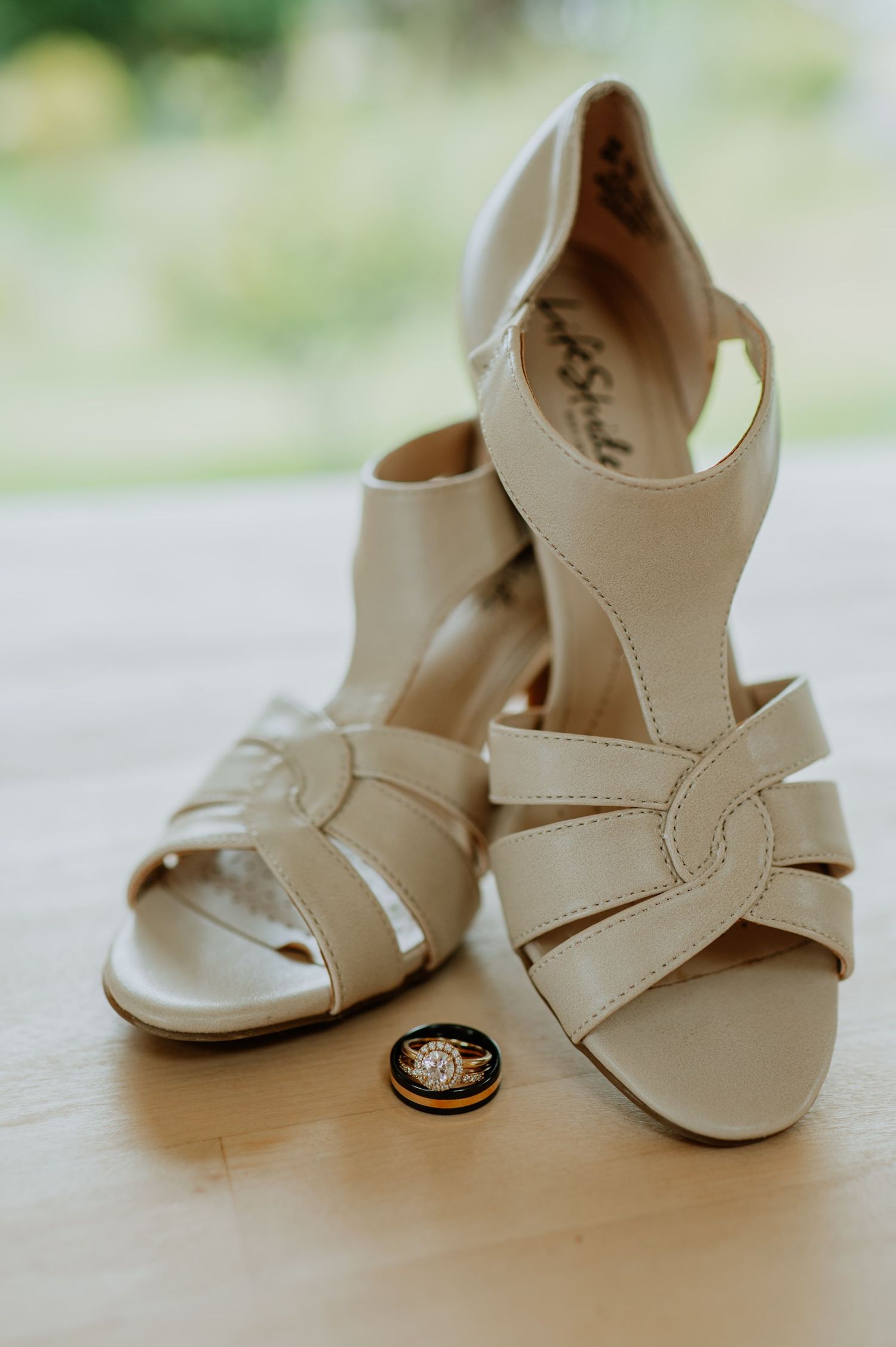 Elegant cream colored bridal sandals with wedding ring detail on light surface.