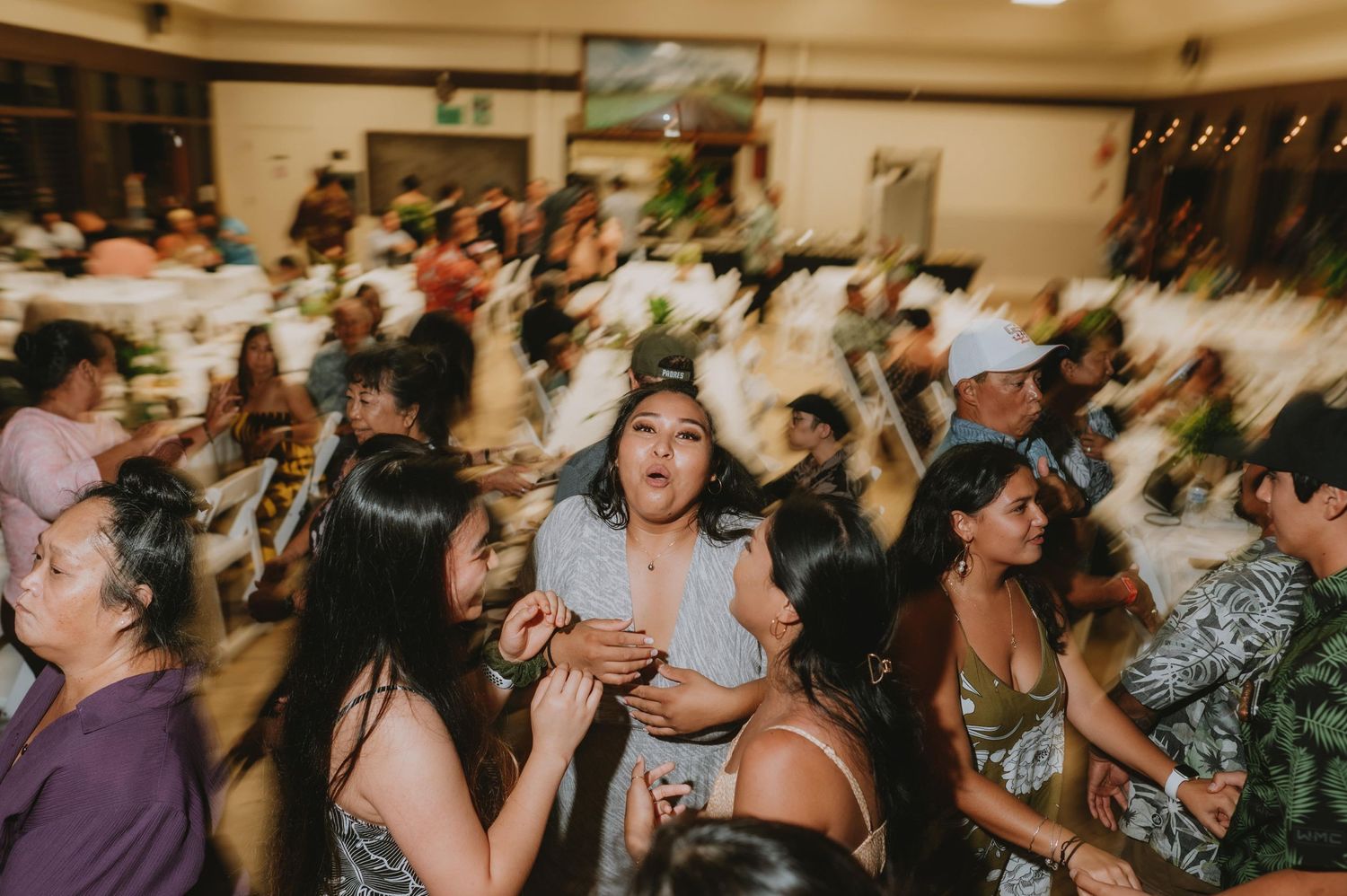 Crowded wedding reception with guests dancing and celebrating in an indoor venue.