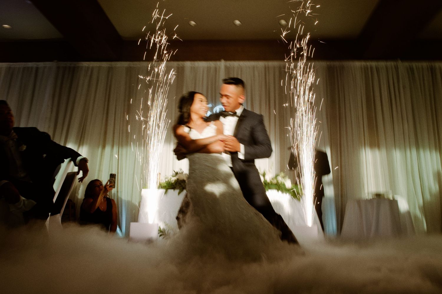 Bride and groom share first dance surrounded by sparkling fireworks and romantic fog on their wedding night.