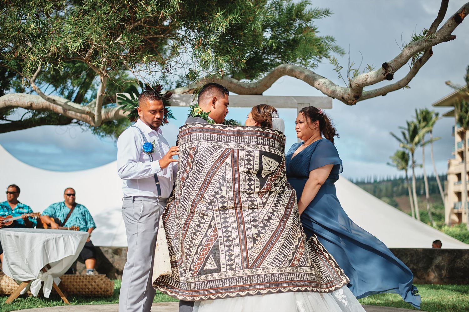 Wedding guests mingle during outdoor reception with palm trees.