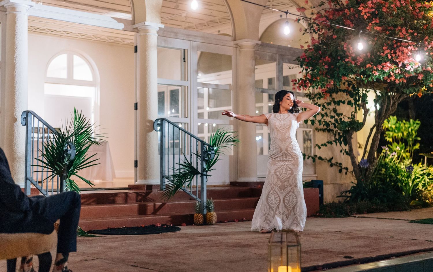 Wedding celebration on an elegant veranda with string lights and tropical landscaping.