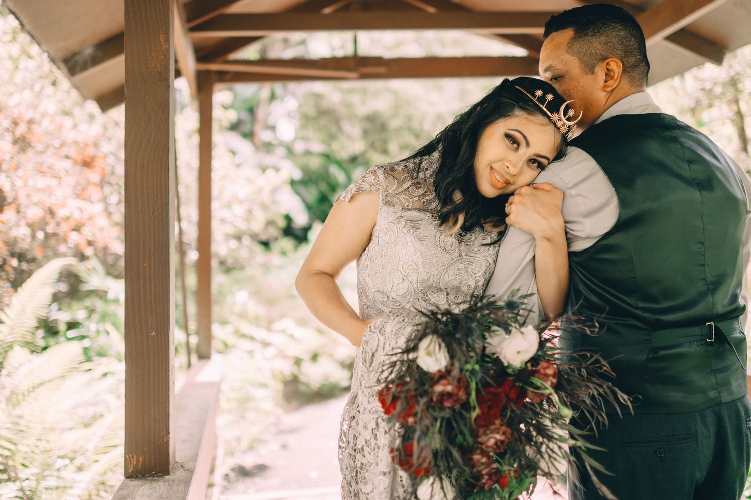 Romantic outdoor wedding ceremony moment captured under a wooden pergola.
