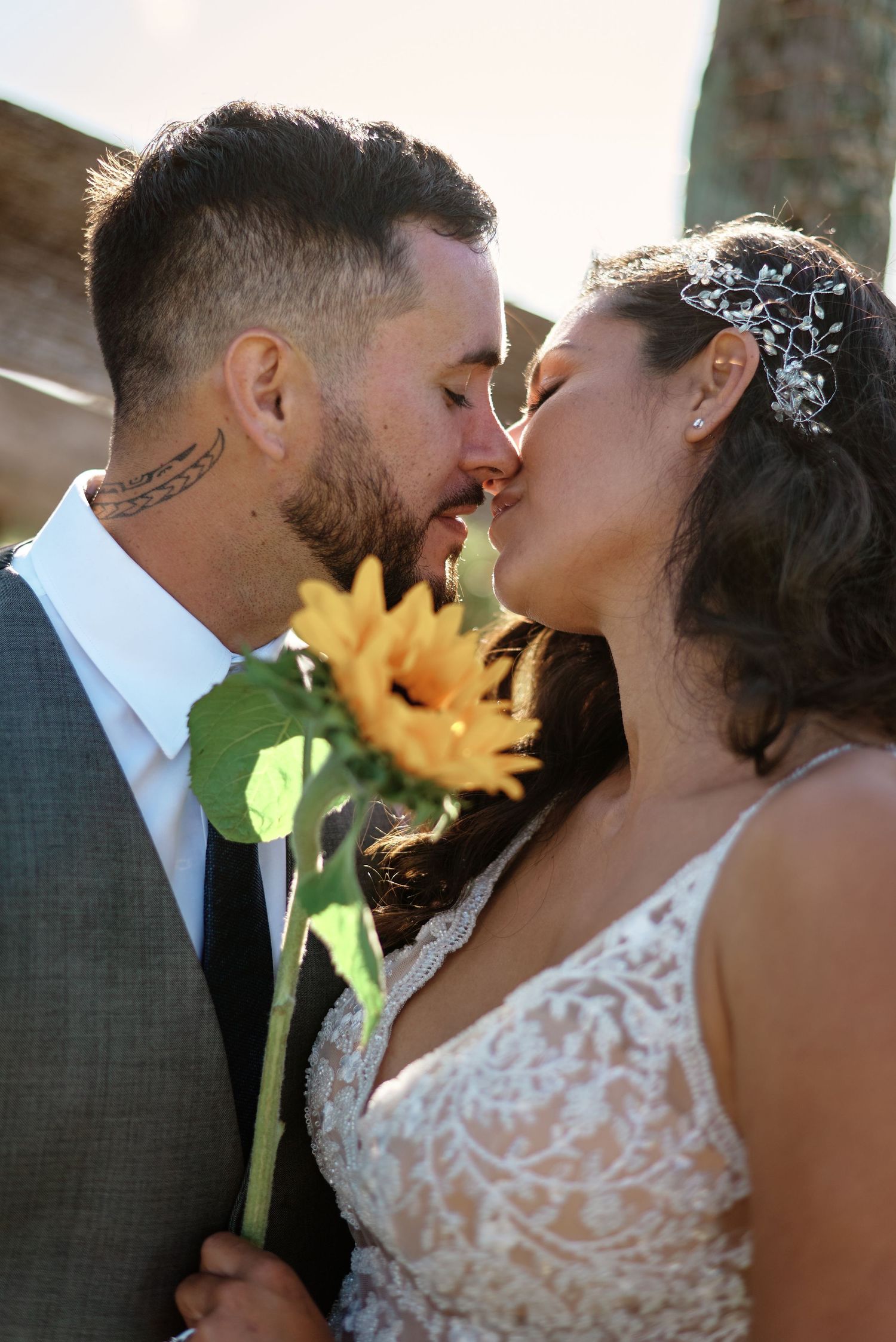 Romantic moment with sunflower between newlyweds in golden afternoon light.