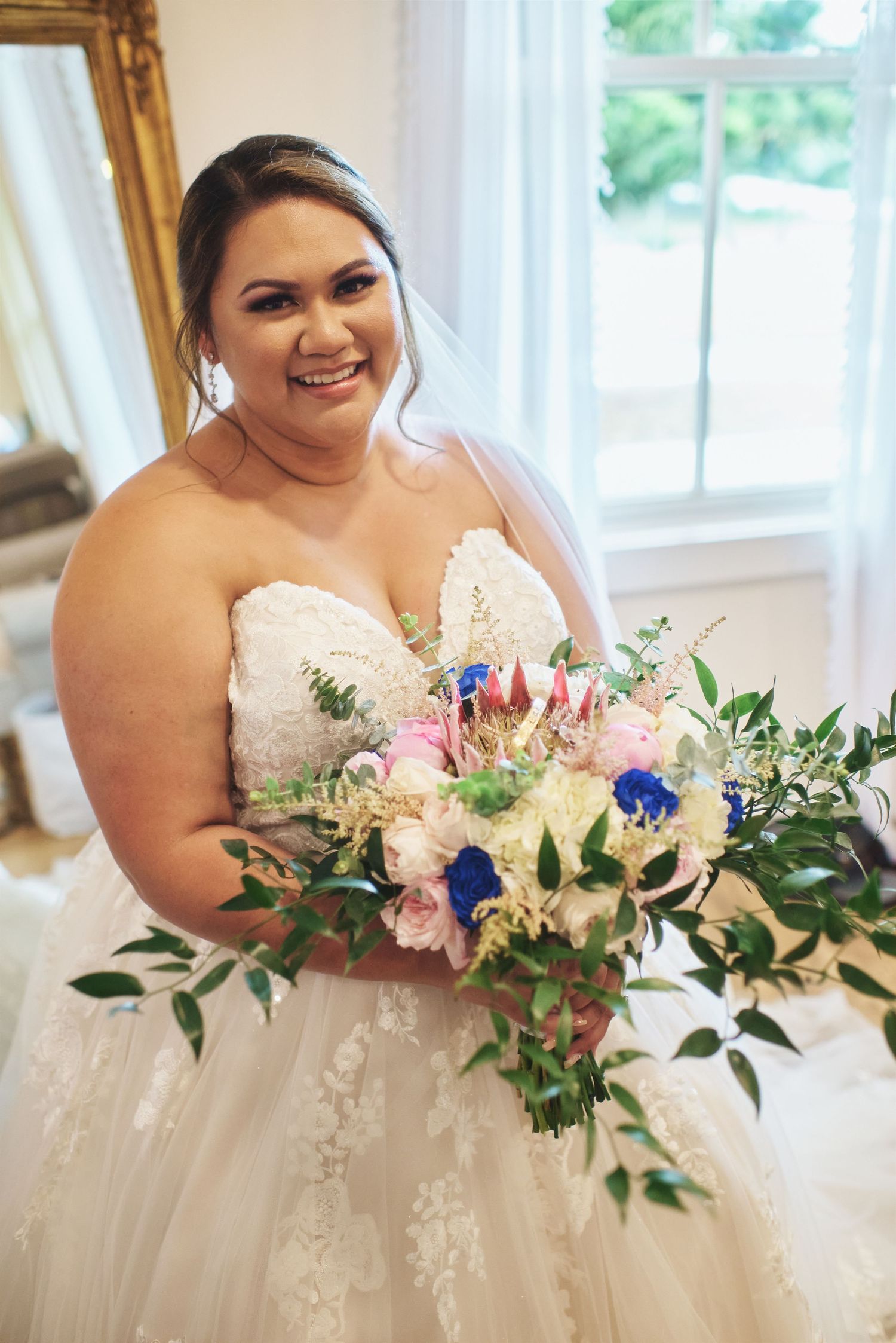 Beautiful bridal bouquet features pink and blue flowers with lush greenery.