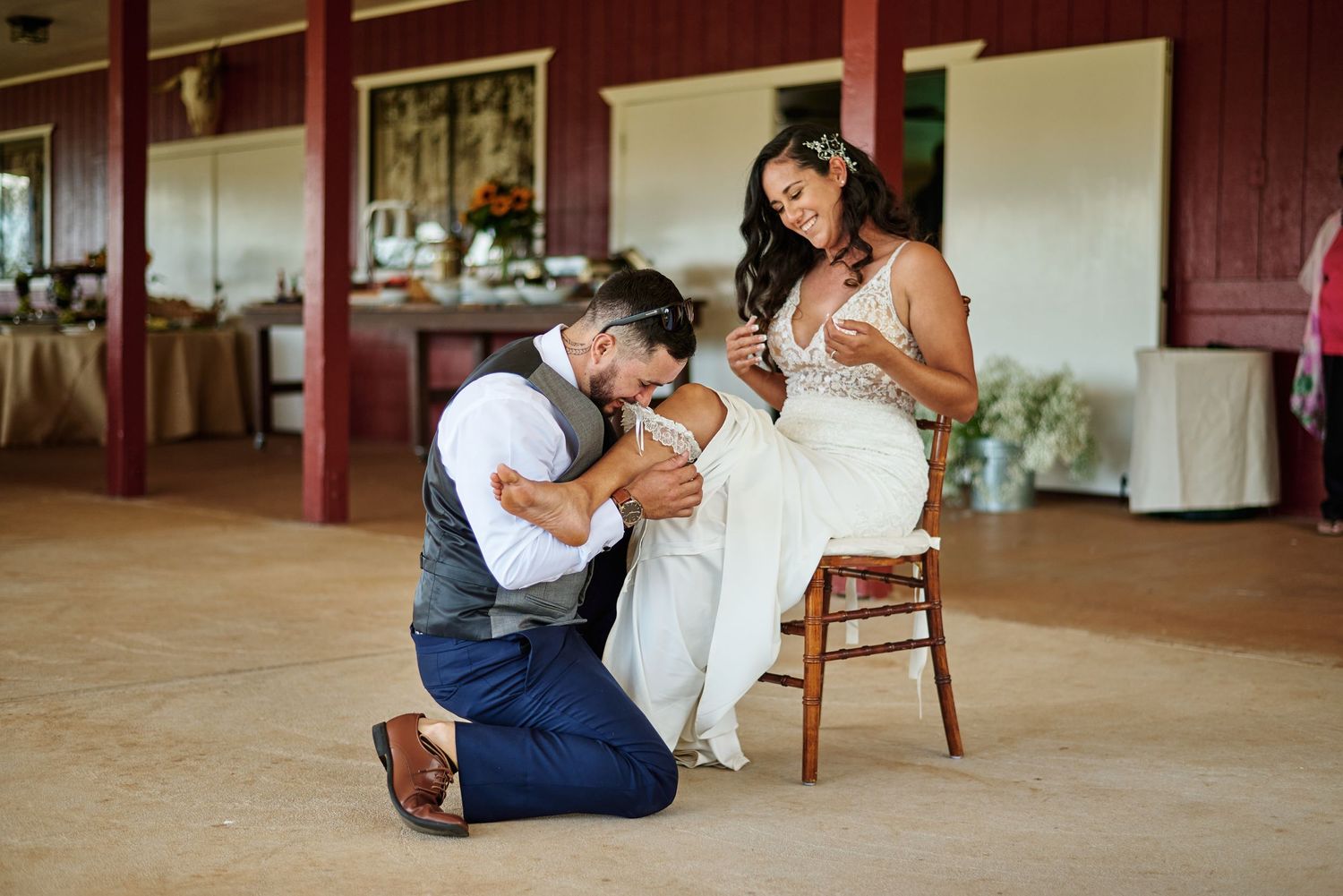 Sweet moment during wedding reception as couple shares intimate gesture on wooden chair.