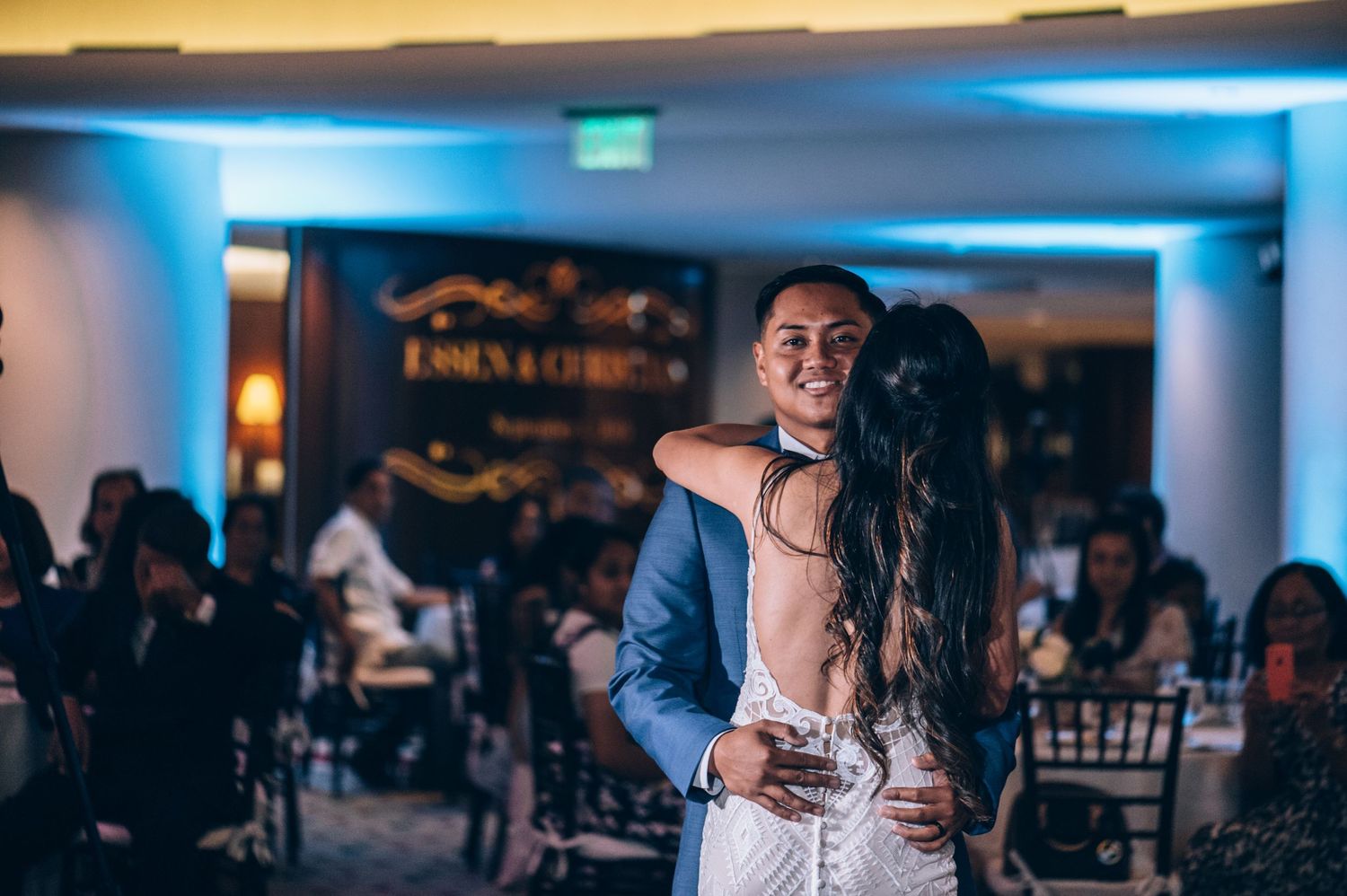 A couple dances together at their wedding reception while guests look on.