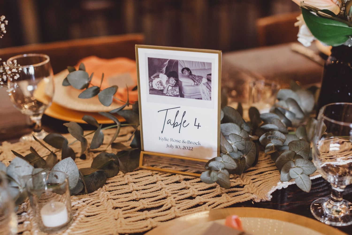 Elegant wedding table setting with Table 4 sign featuring a vintage photo, eucalyptus greenery, and gold accents.