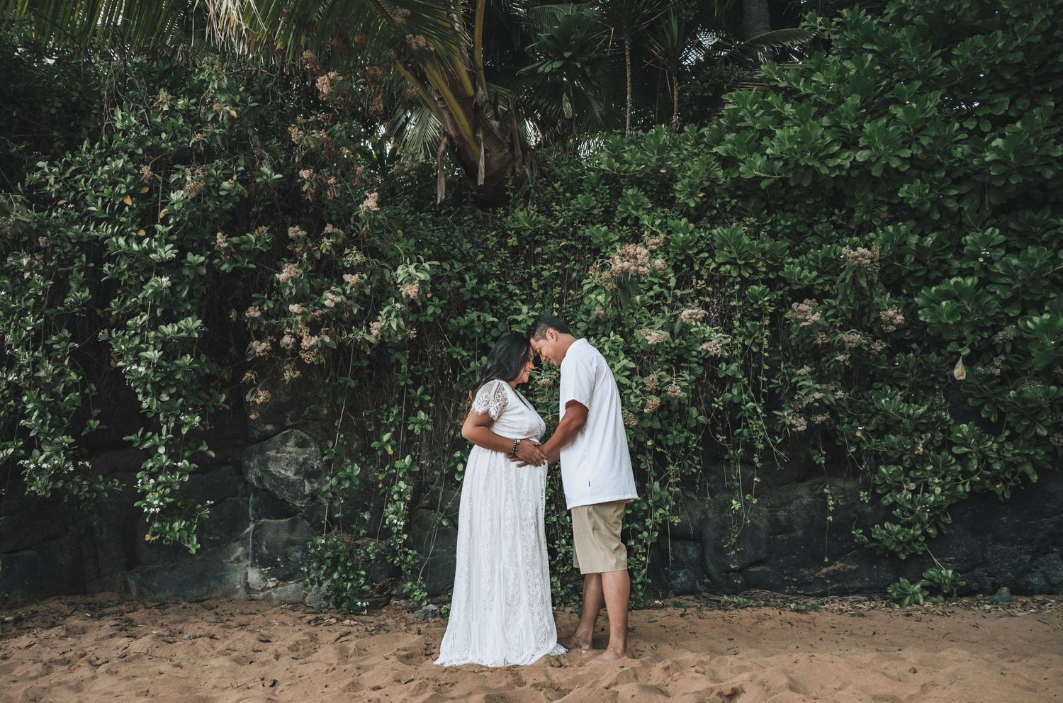 Romantic beach wedding photos captured against a backdrop of tropical greenery and sand.