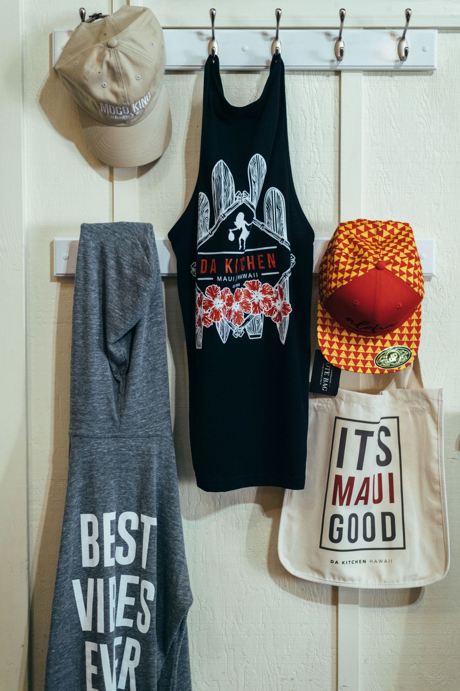 Retail merchandise display with casual clothing and accessories hanging on wall hooks.
