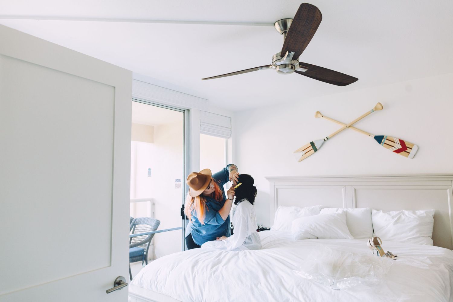 Two people jumping playfully on a white bed in a bright modern bedroom.